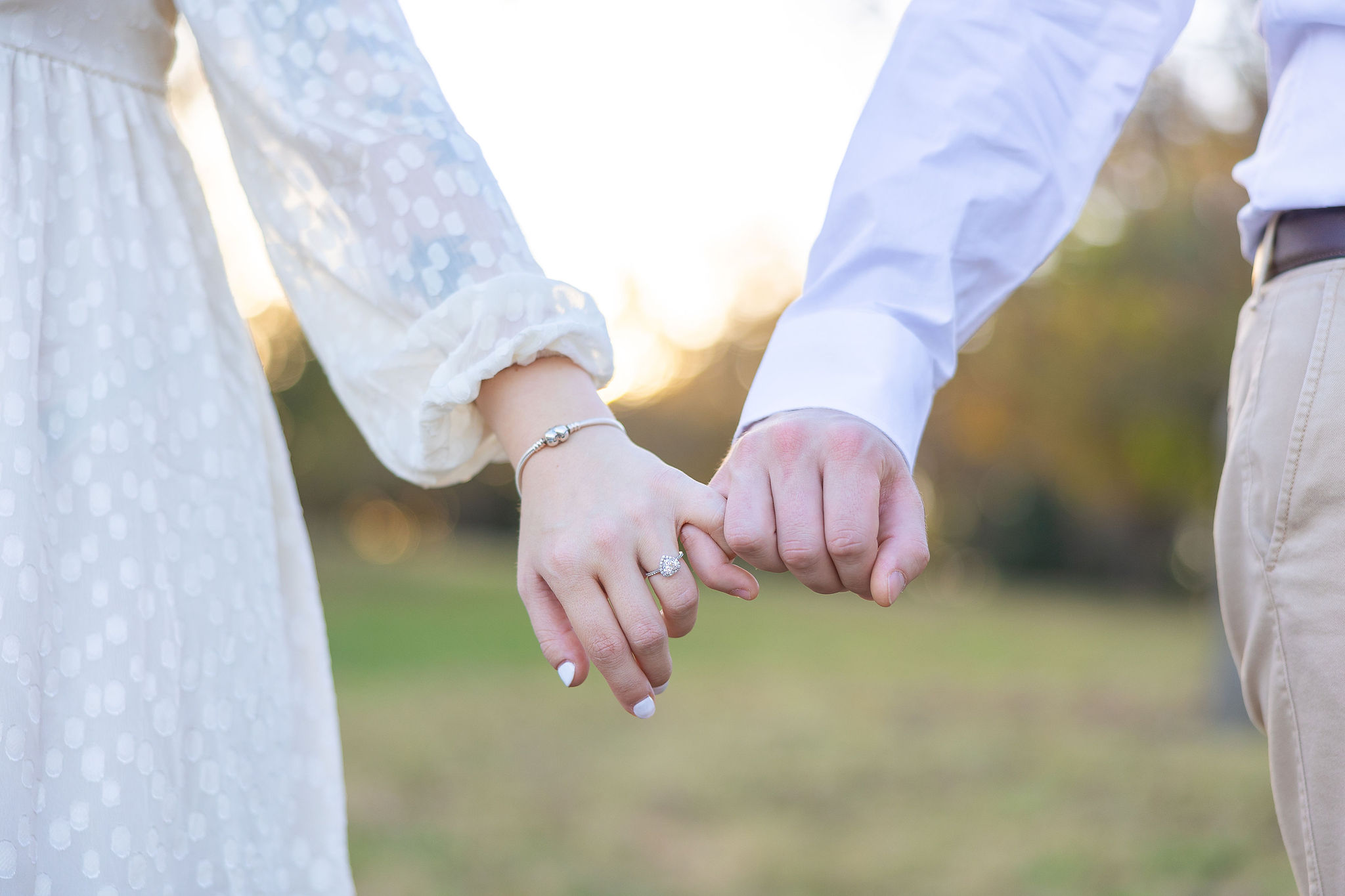 Couple interlocking pinkies with engagement rings on