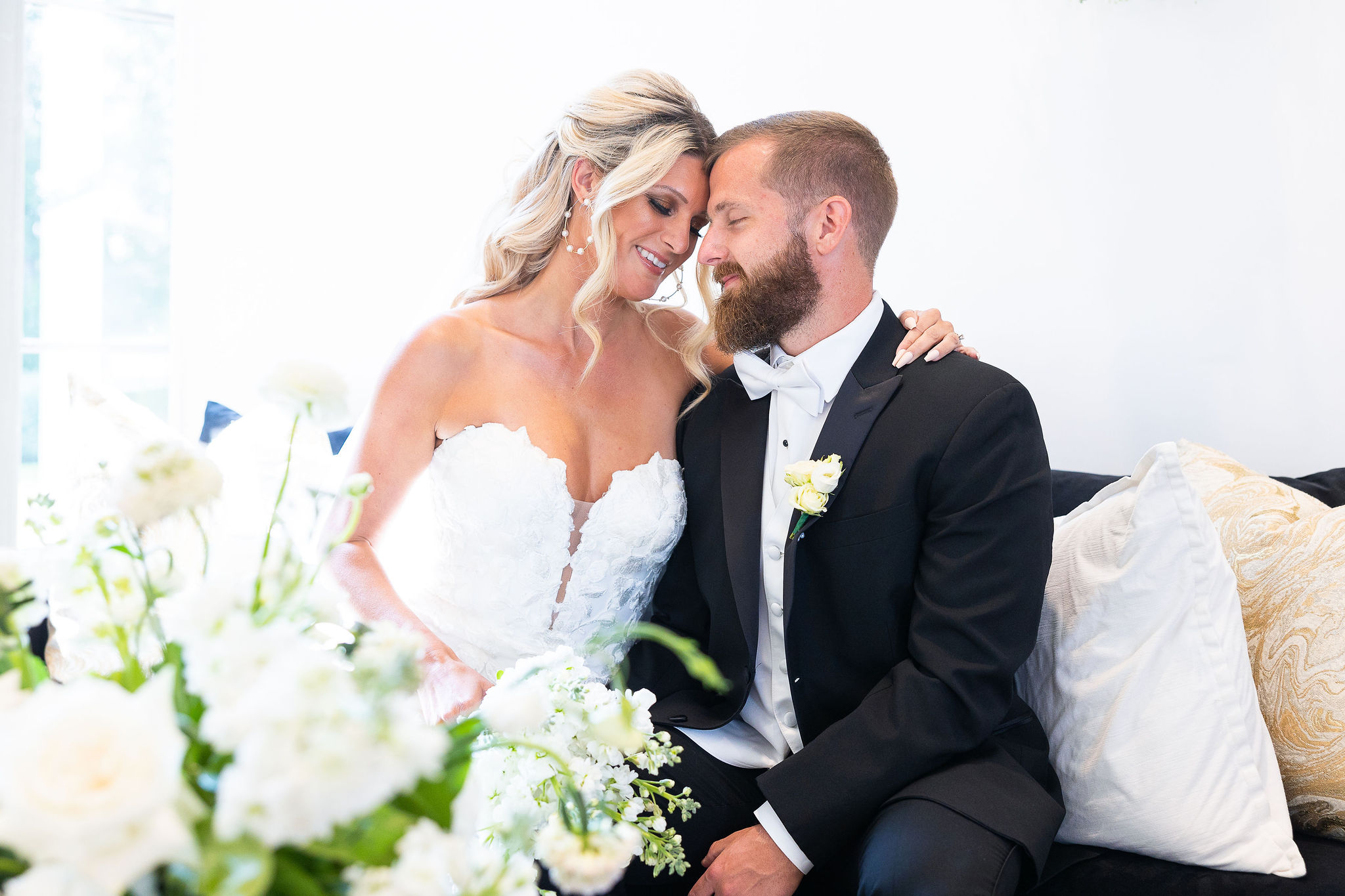 Bride and groom sitting on couch with white bouquet