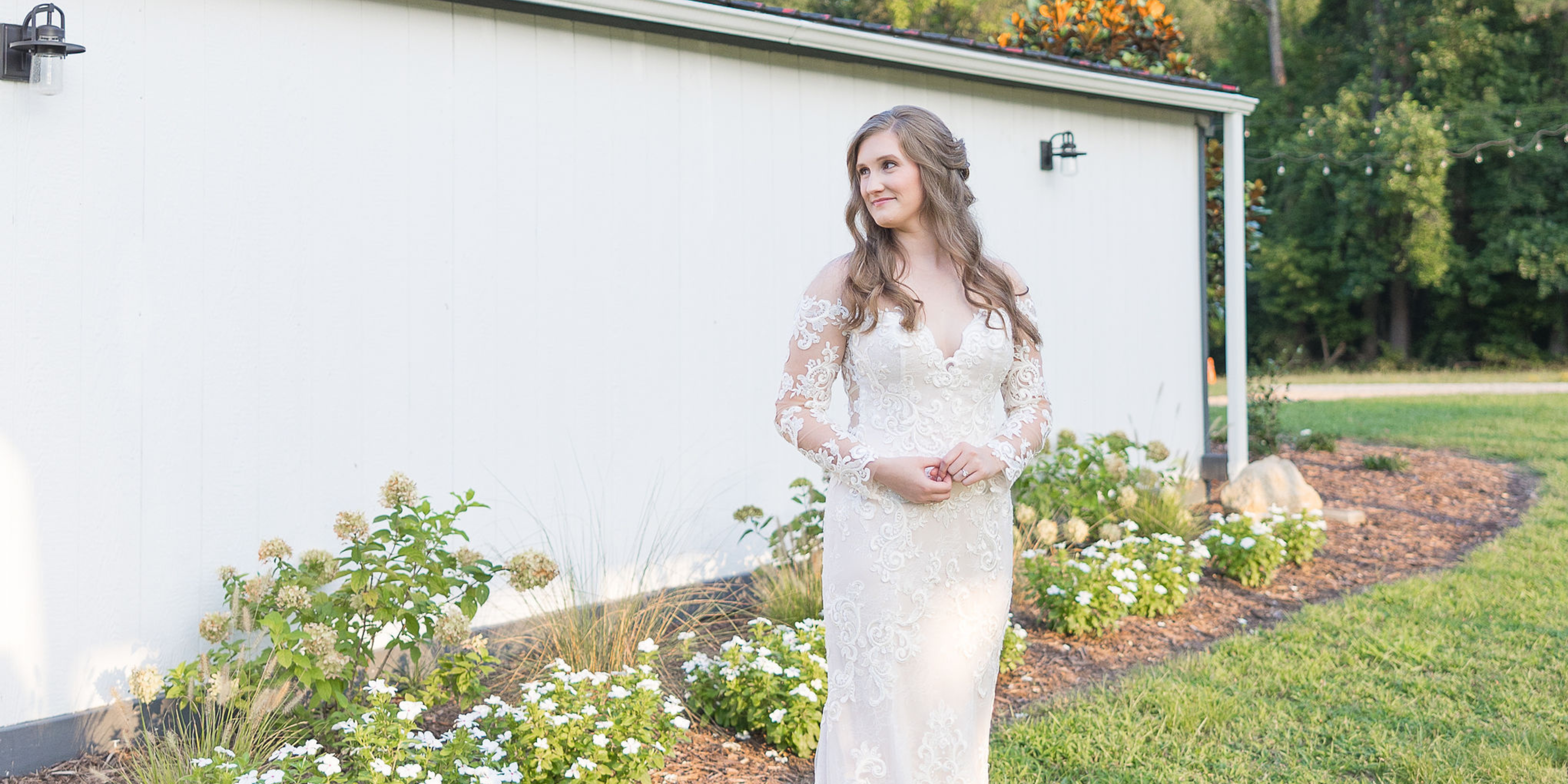 Bride Looking to Side in Lace Wedding Gown at White Barn