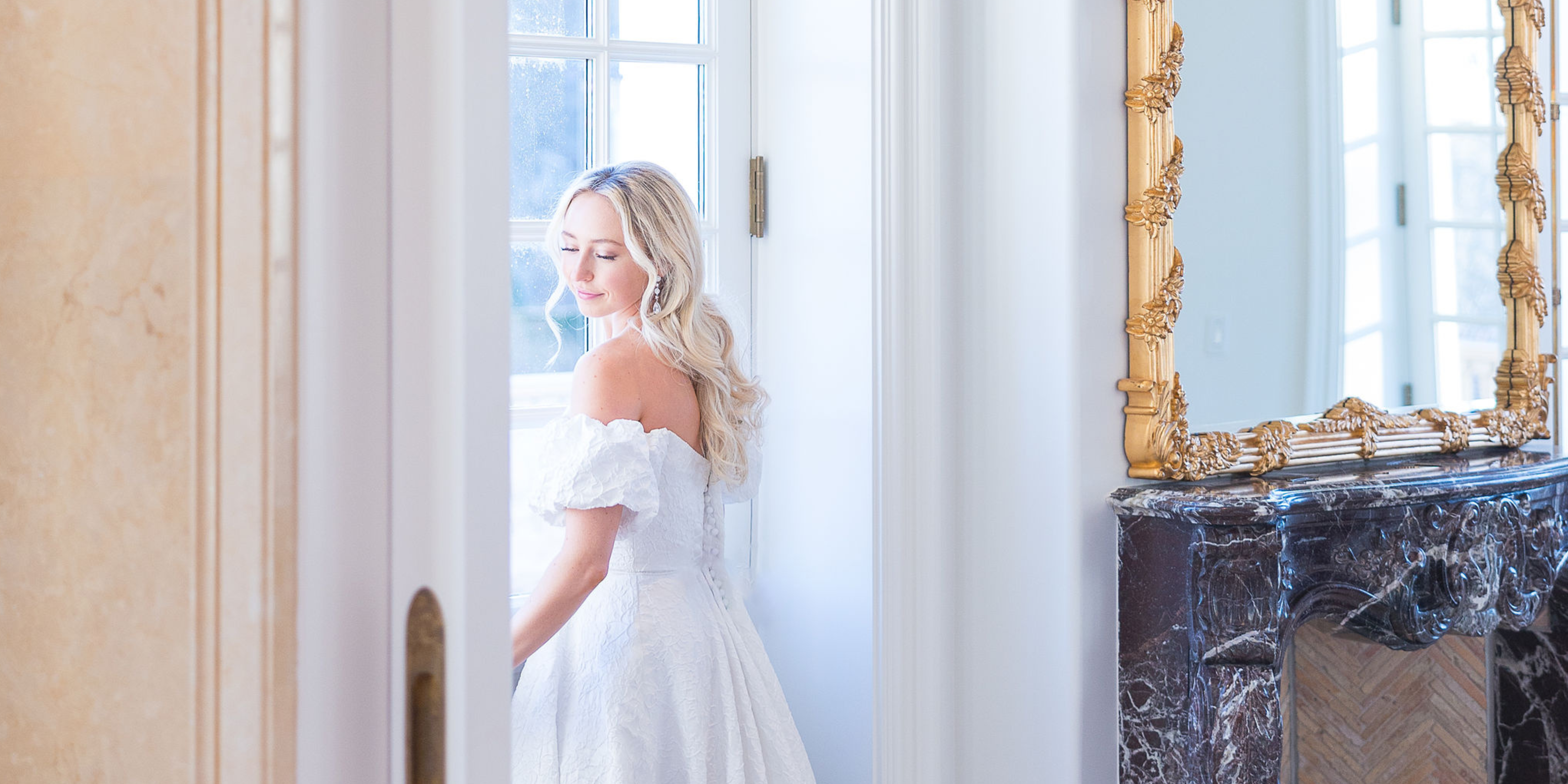 Bride looking out the window in wedding gown