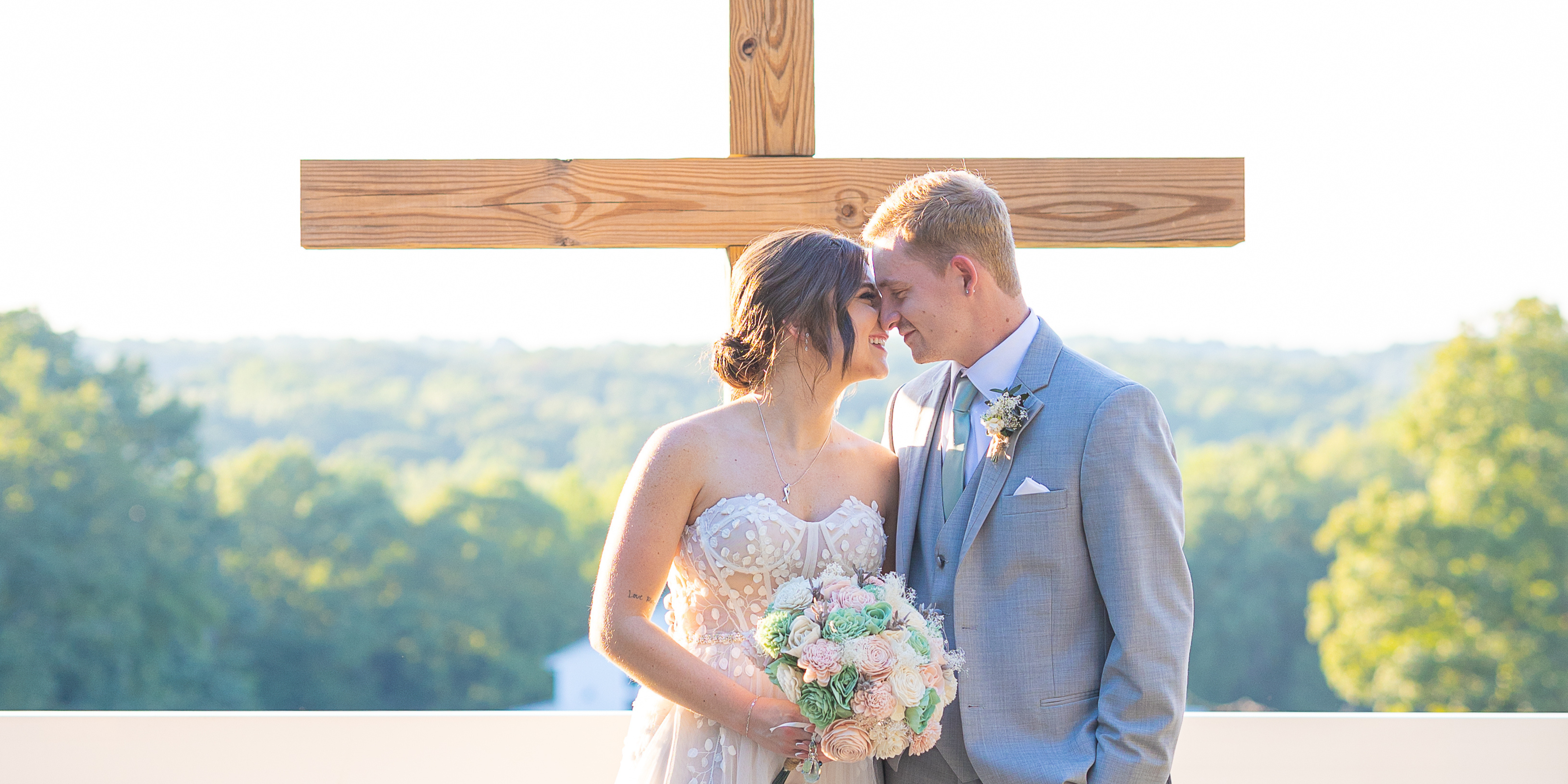 Couple standing at a cross with wedding bouquet