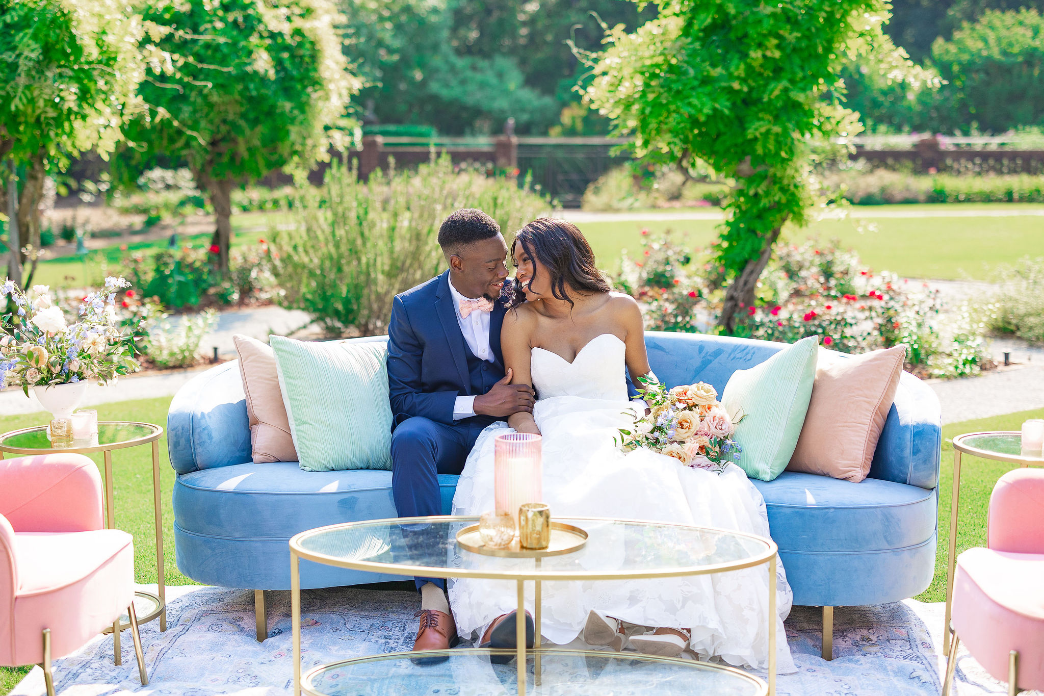 Bride and Groom aitting on couch outside with colorful pillows