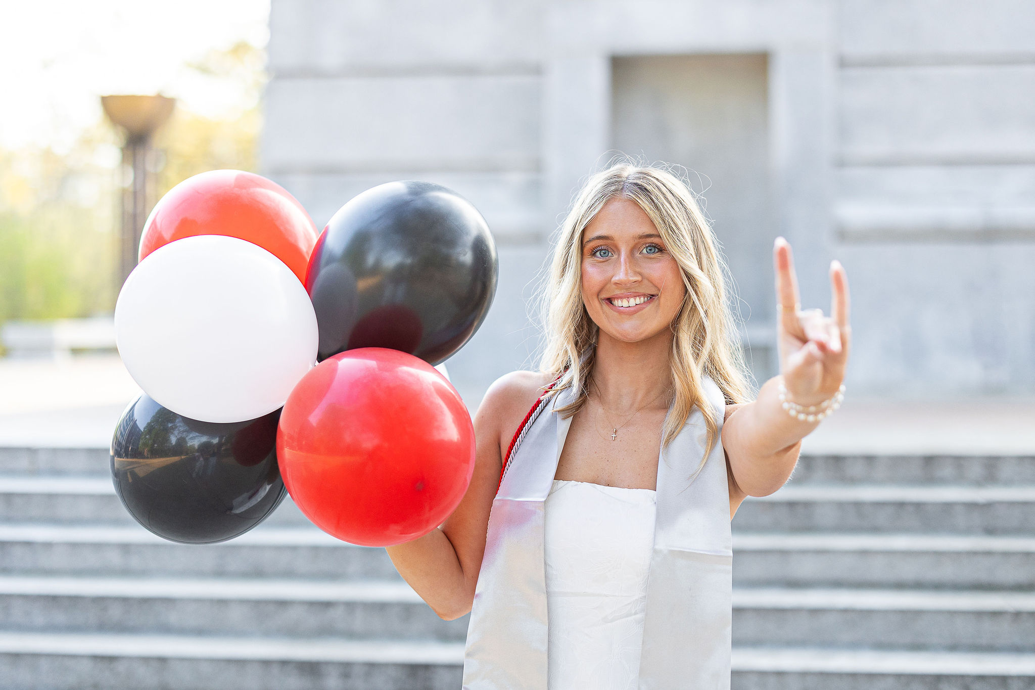 NC State graduation session with red, white, and black balloons holding up wolf ears