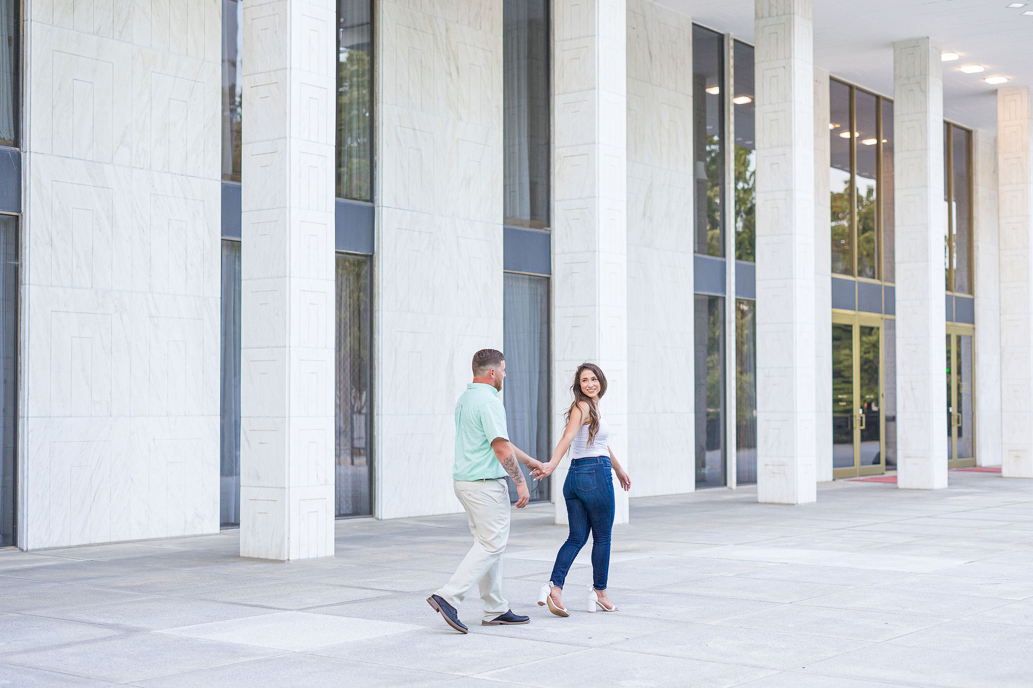 Couple walking and holding hands outside downtown building