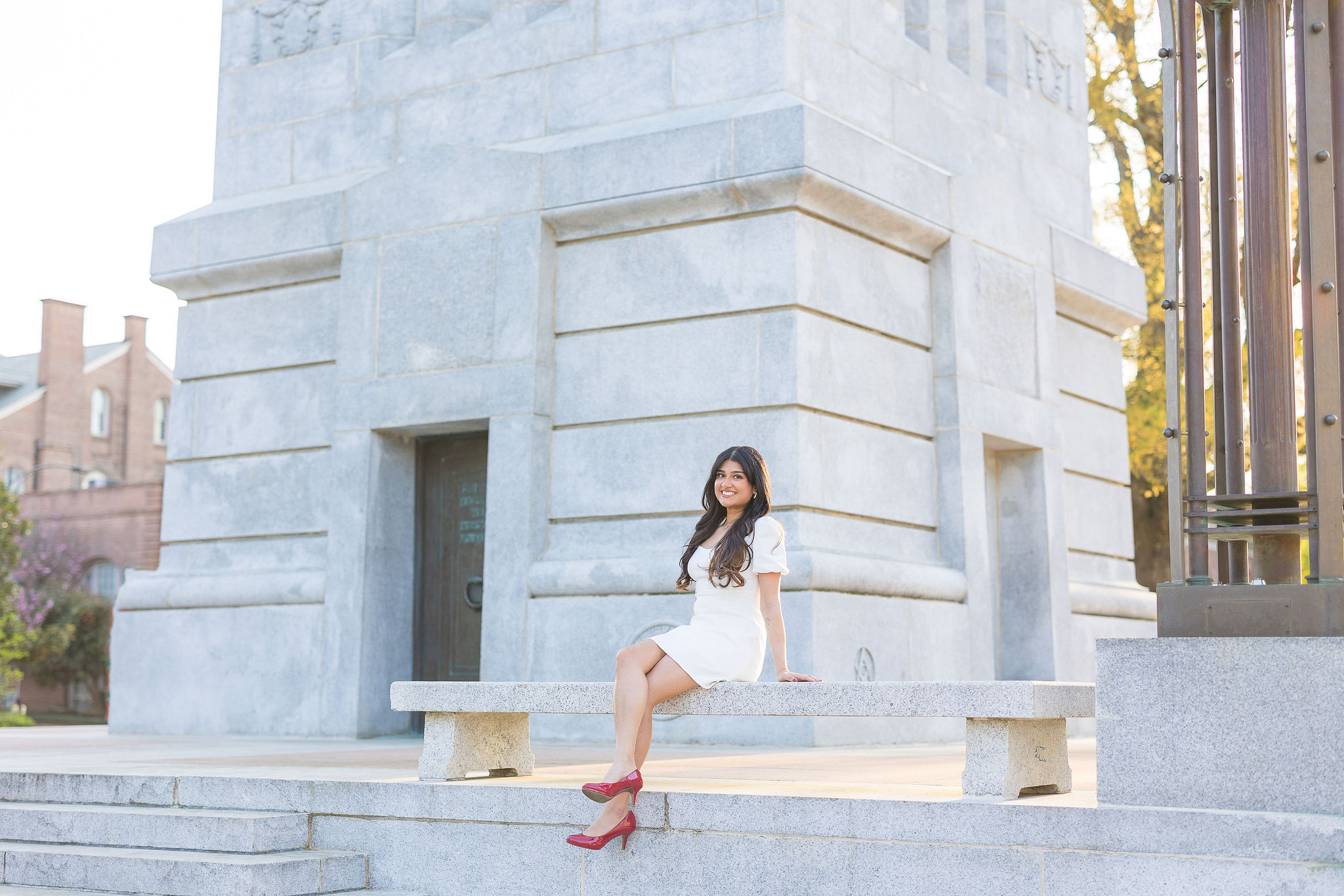 NC State grad sitting on bench at NC State belltower