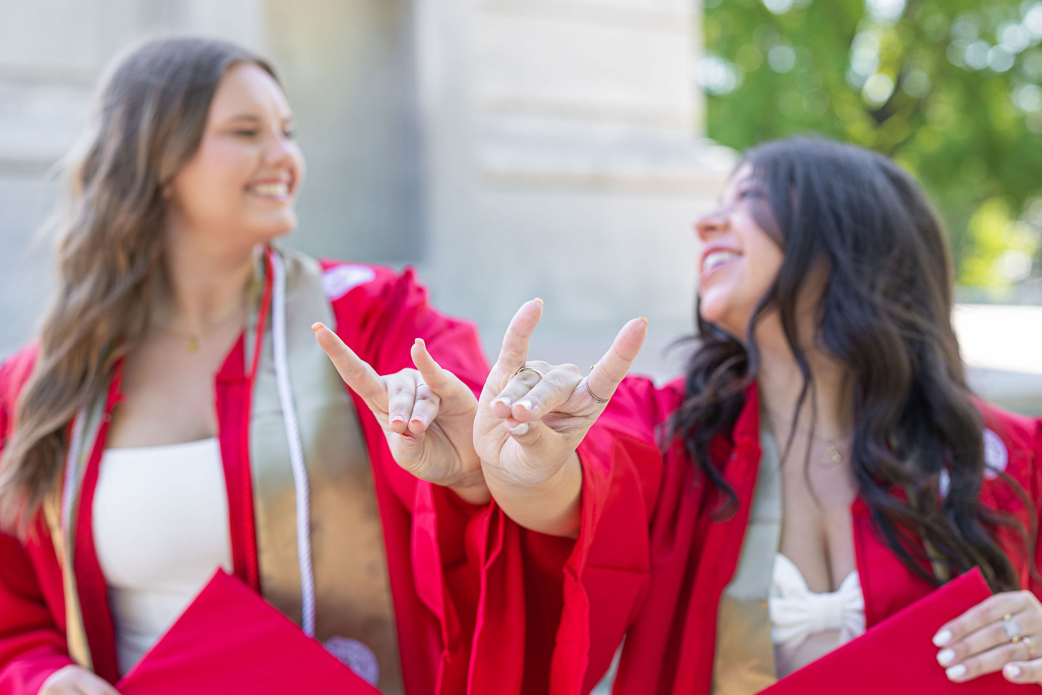 Best friends in cap and gown in front of NC State Belltower