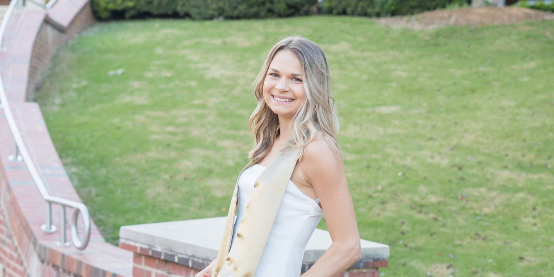 Girl in white lace dress with gold stole in field