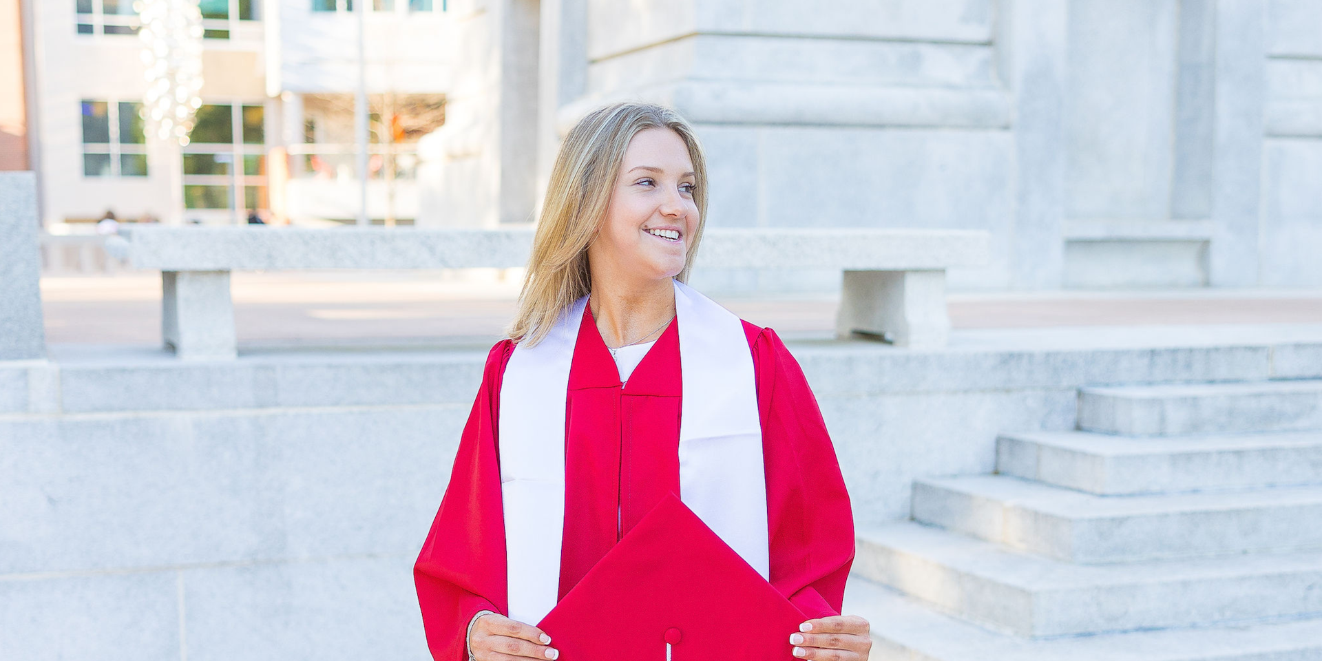 NC State grad looking to the side in red gown at the Belltower