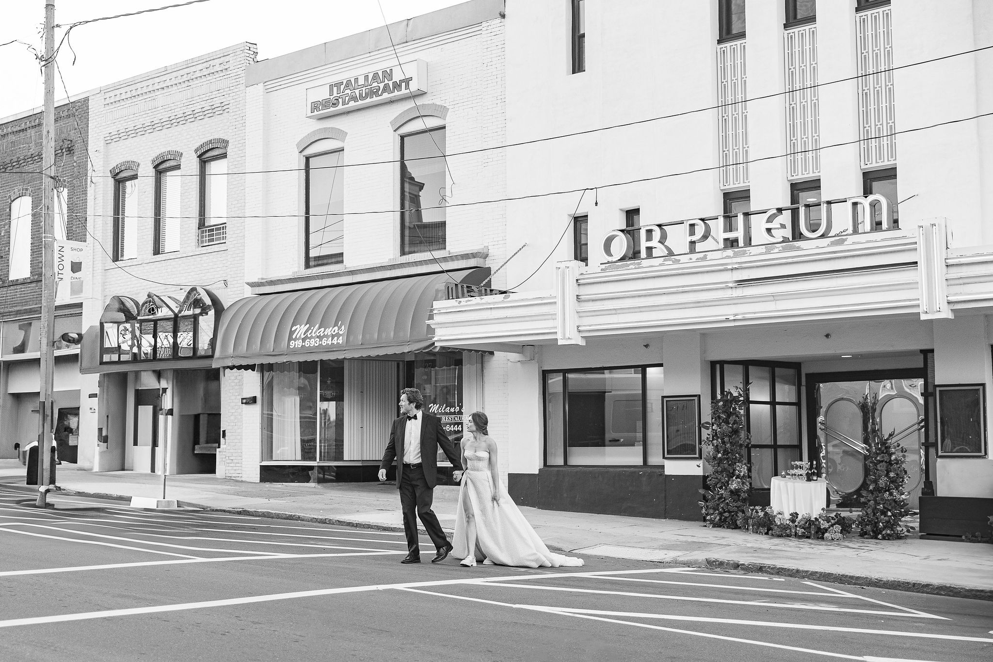 Black and White photo of Bride and Groom walking in front of vintage sign