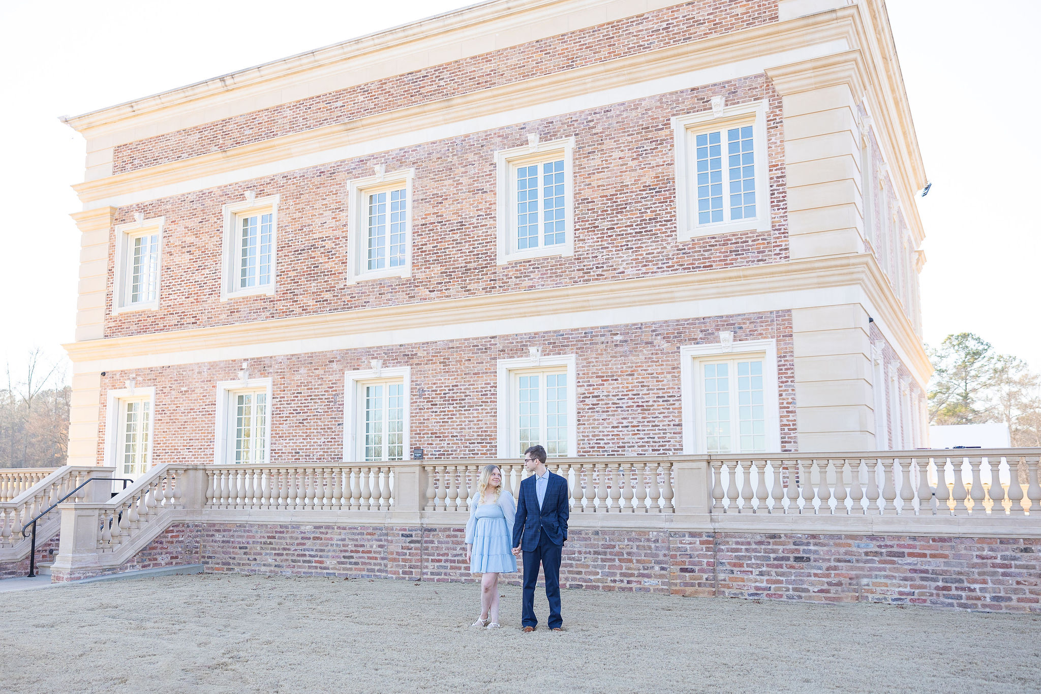 Girl and boy standing together in front of brick building