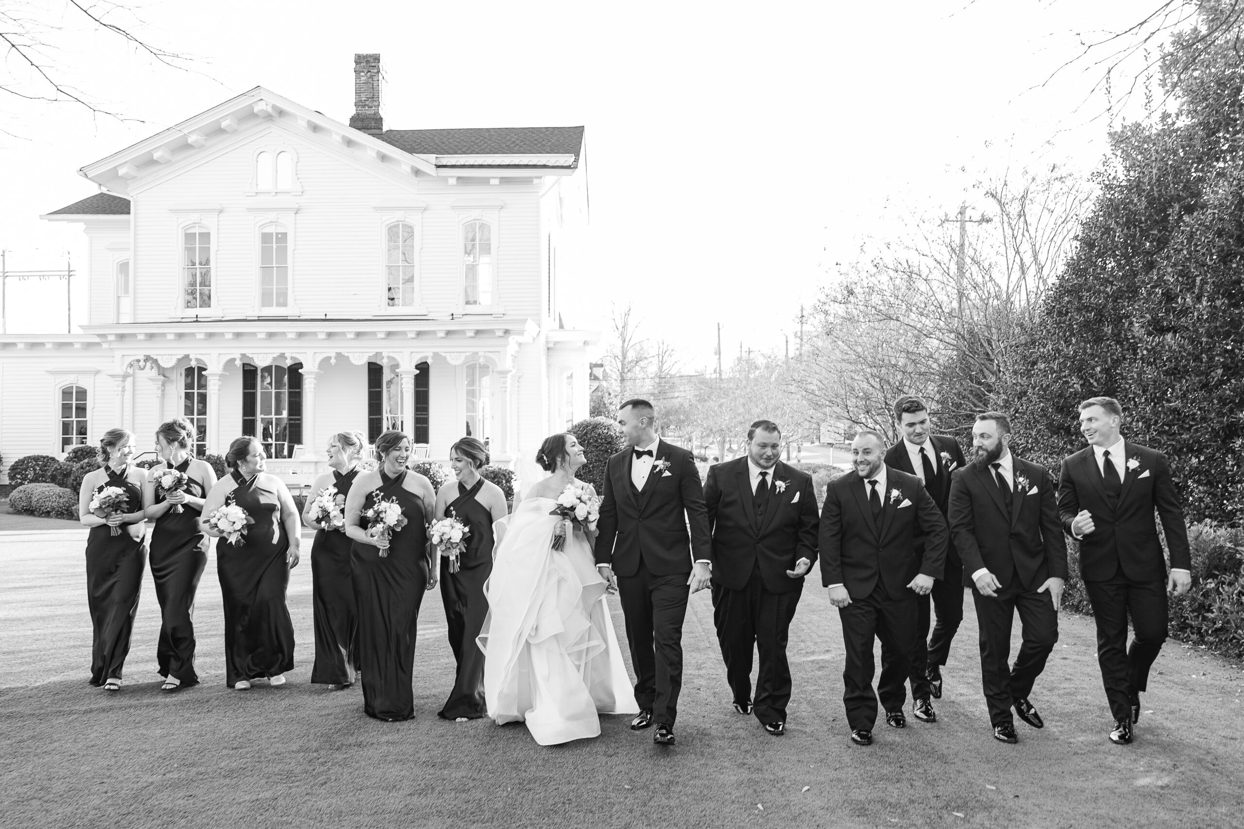 Black and white photo of bride and groom with bridal party surrounding them