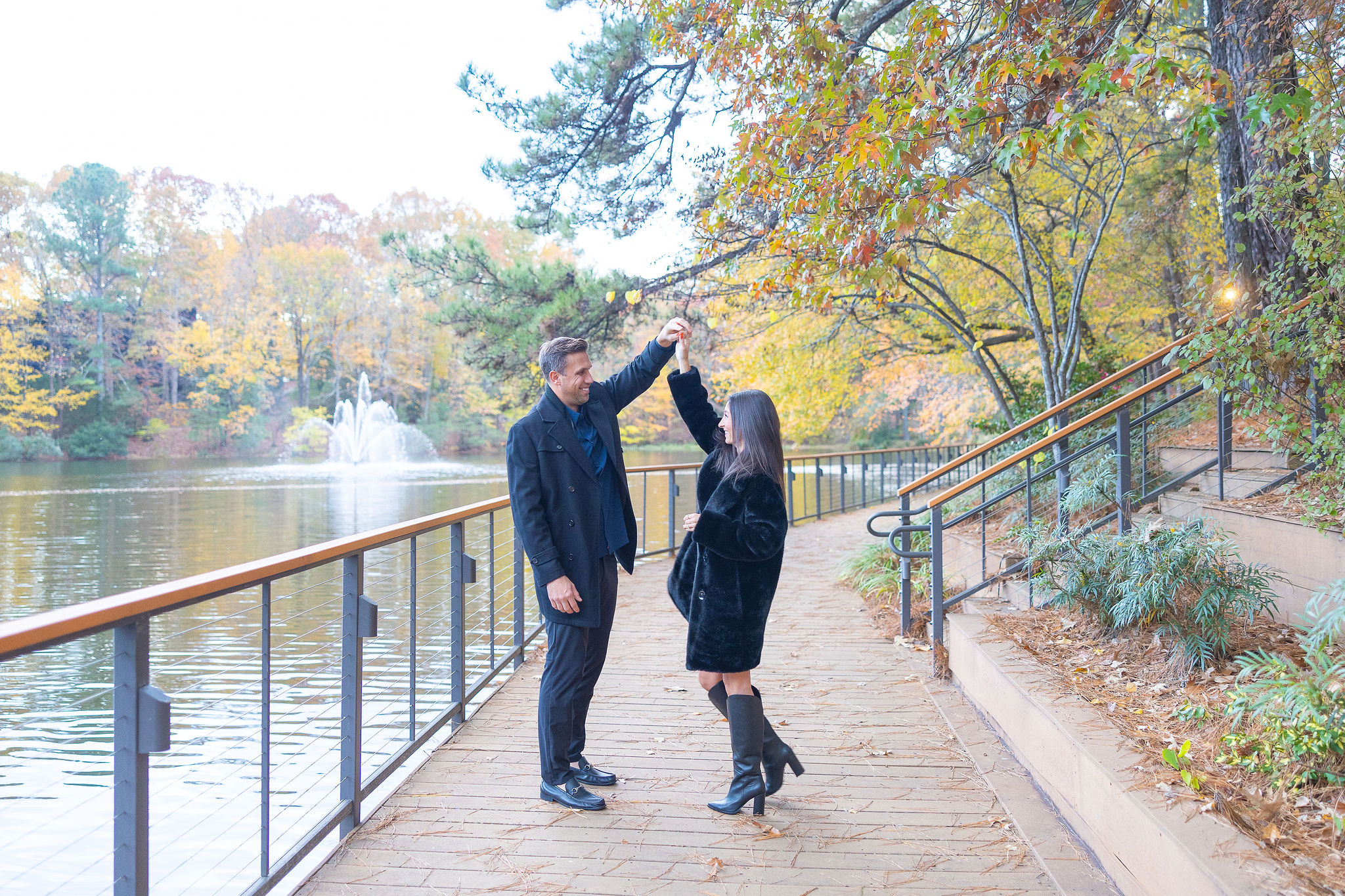 Guy spinning a girl on a bridge near a lake