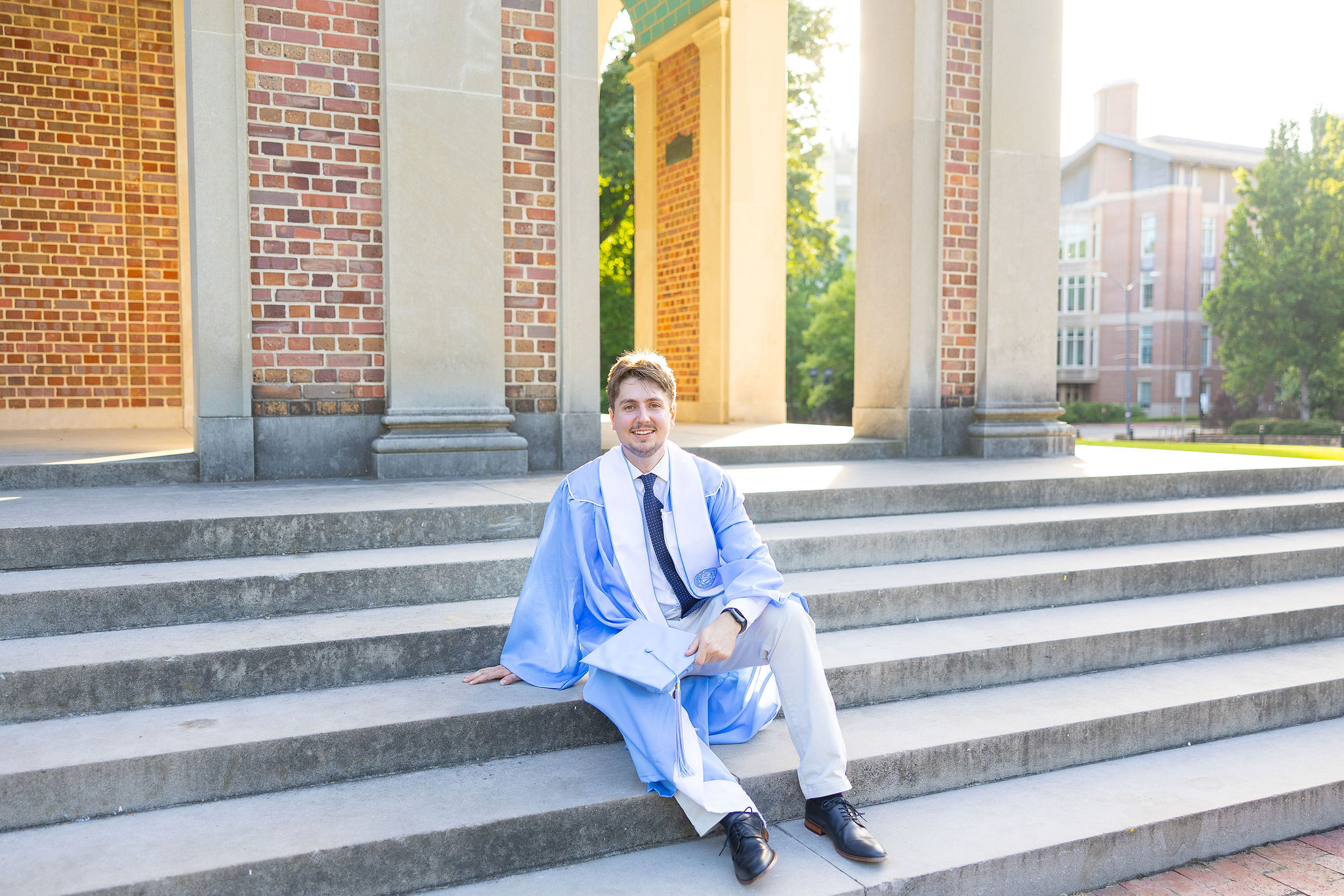 Male UNC Grad sitting on steps in cap and gown
