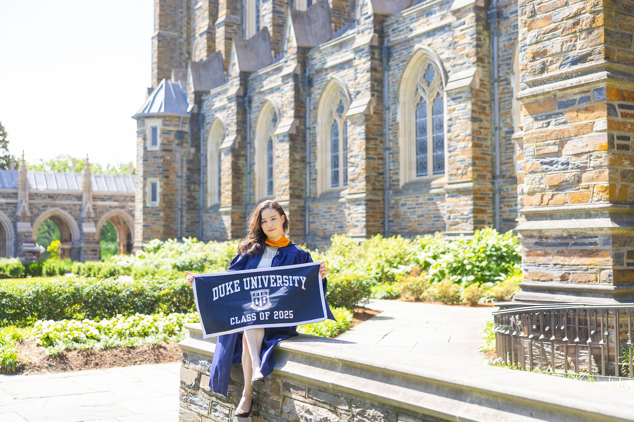 Duke University Graduate holding a Duke flag