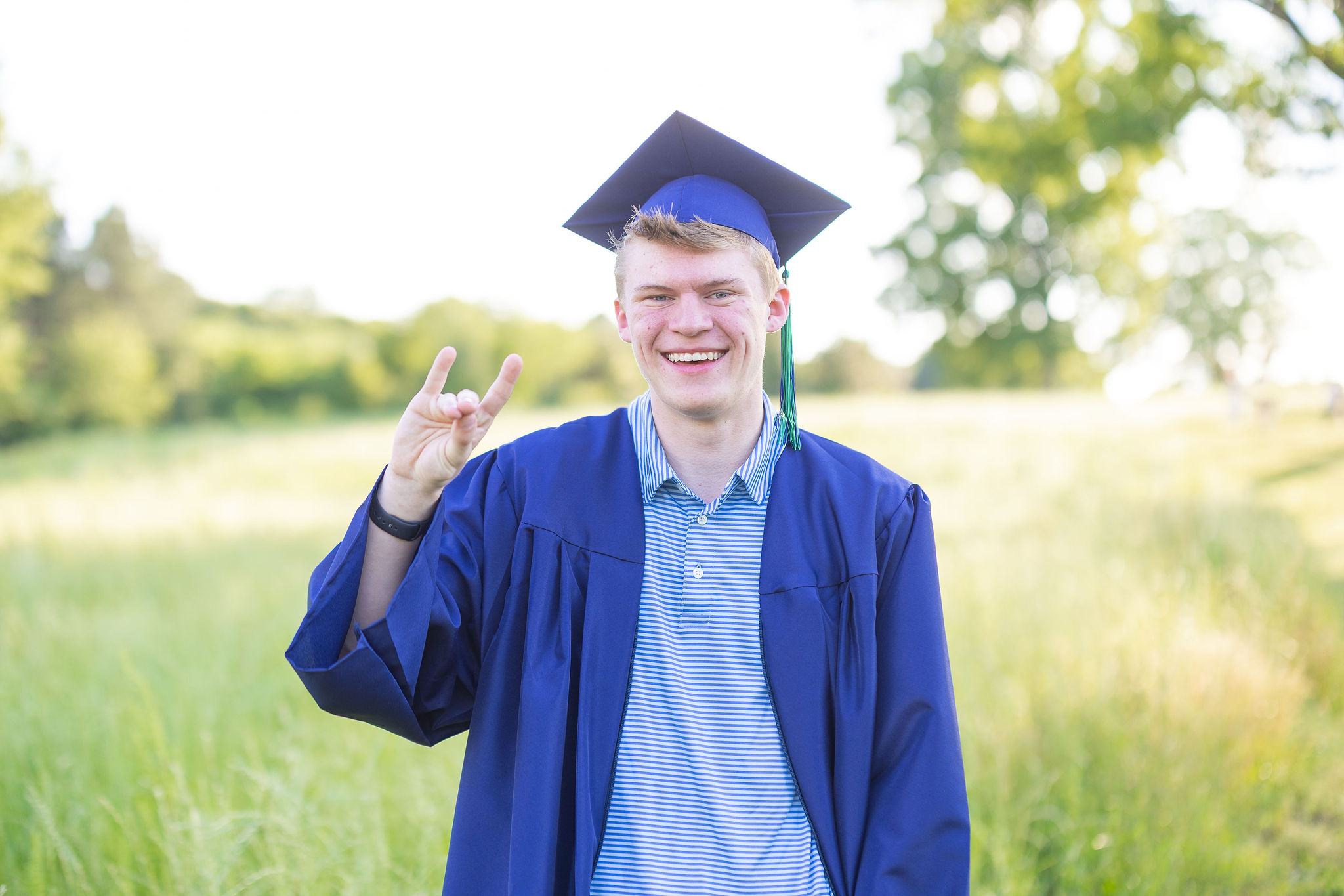 High school senior in field in cap and gown