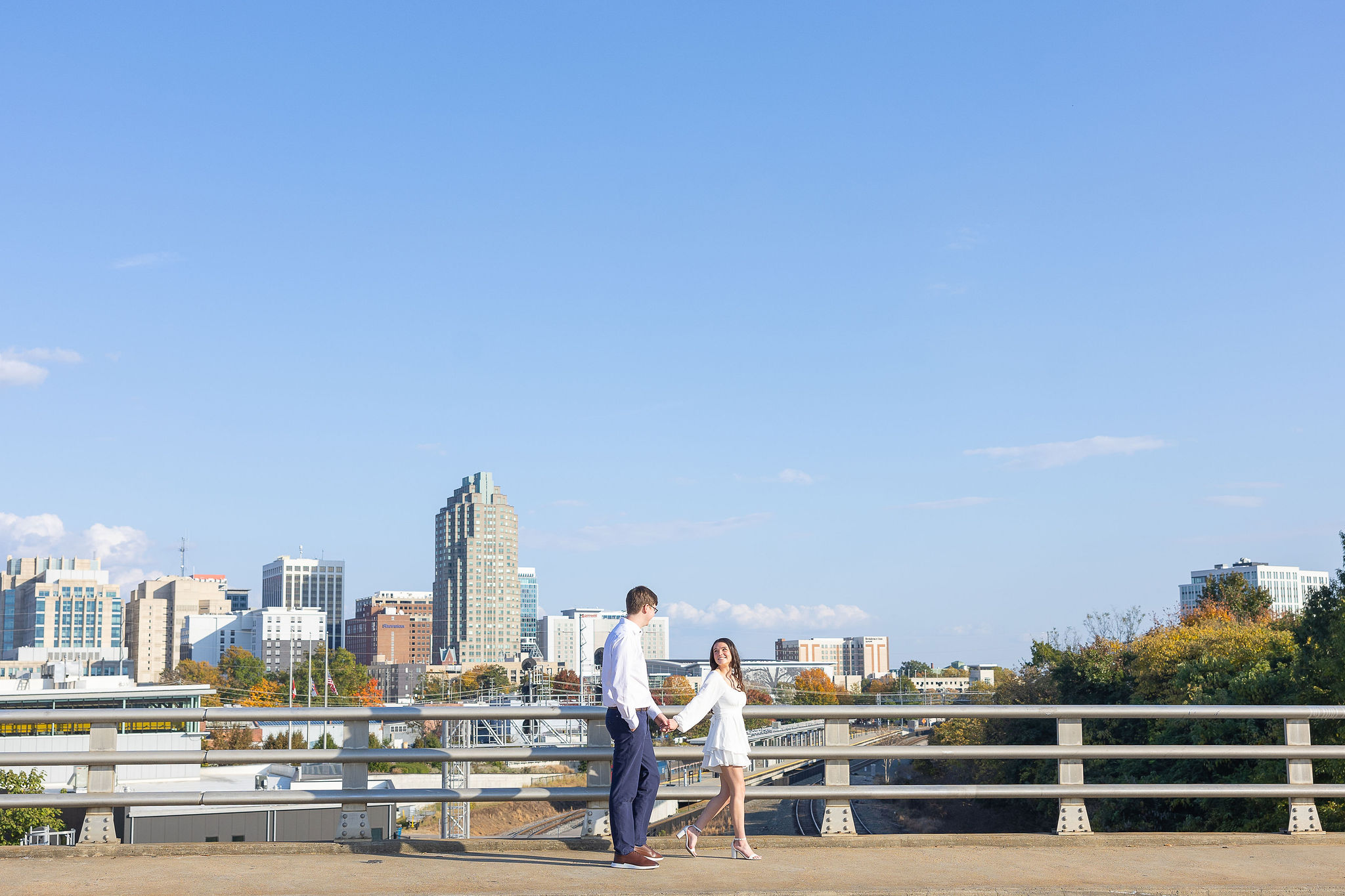 Couple walking on bridge in downtown Raleigh engagement session