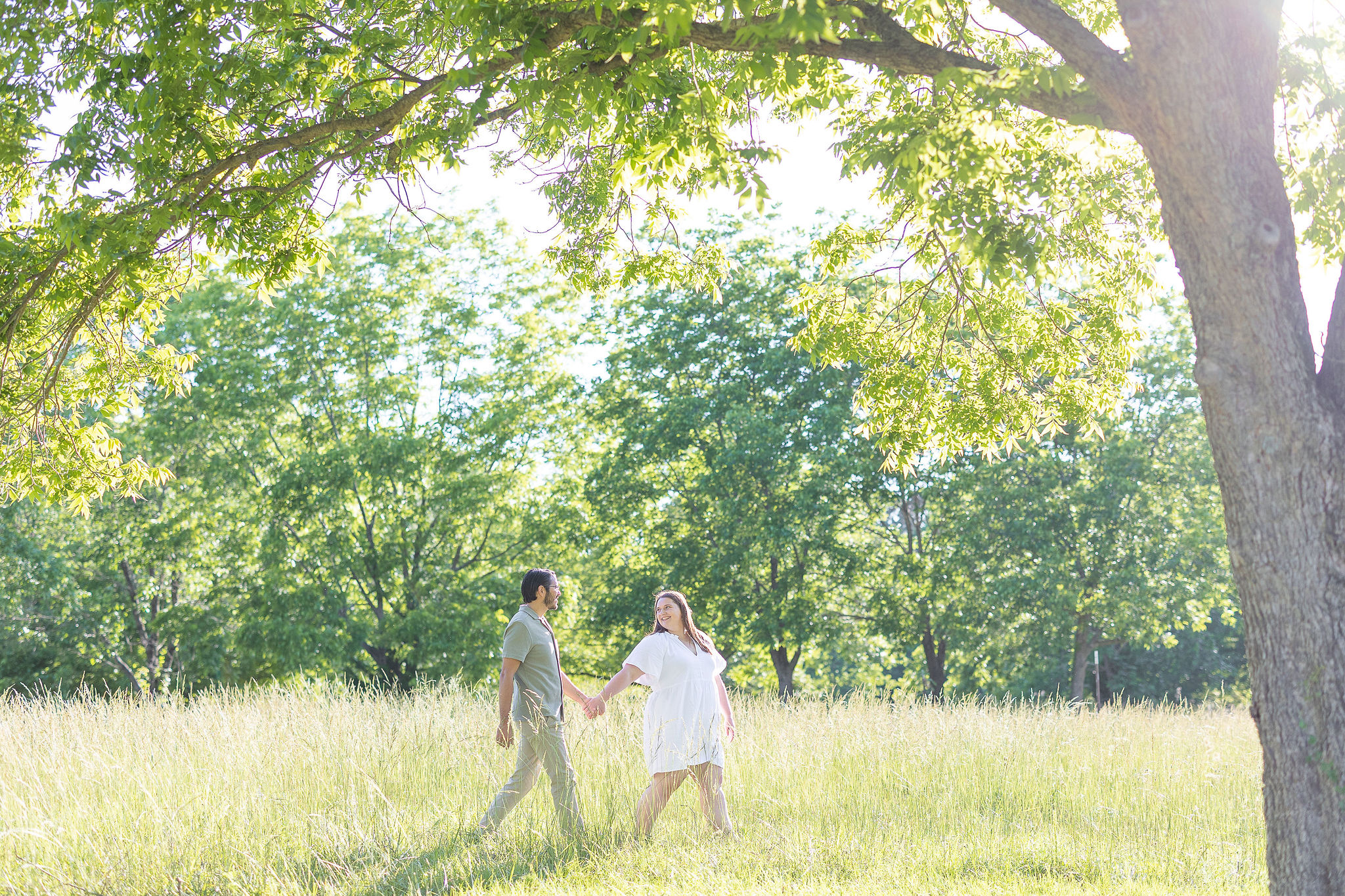 Couple walking in a field holding hands for an enaggement sesssion