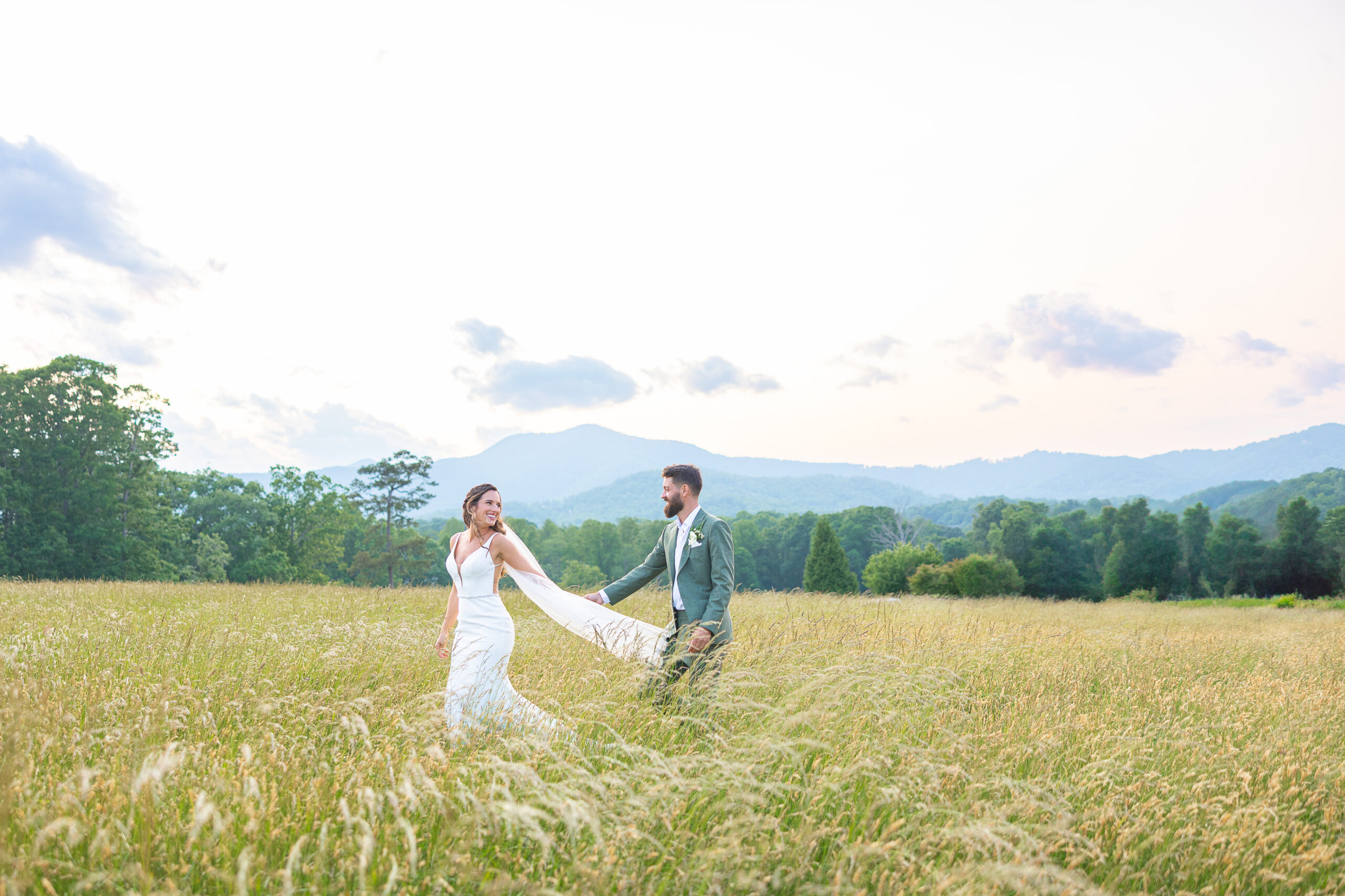 Couple in the fields in Asheville, NC in wedding gown and suit
