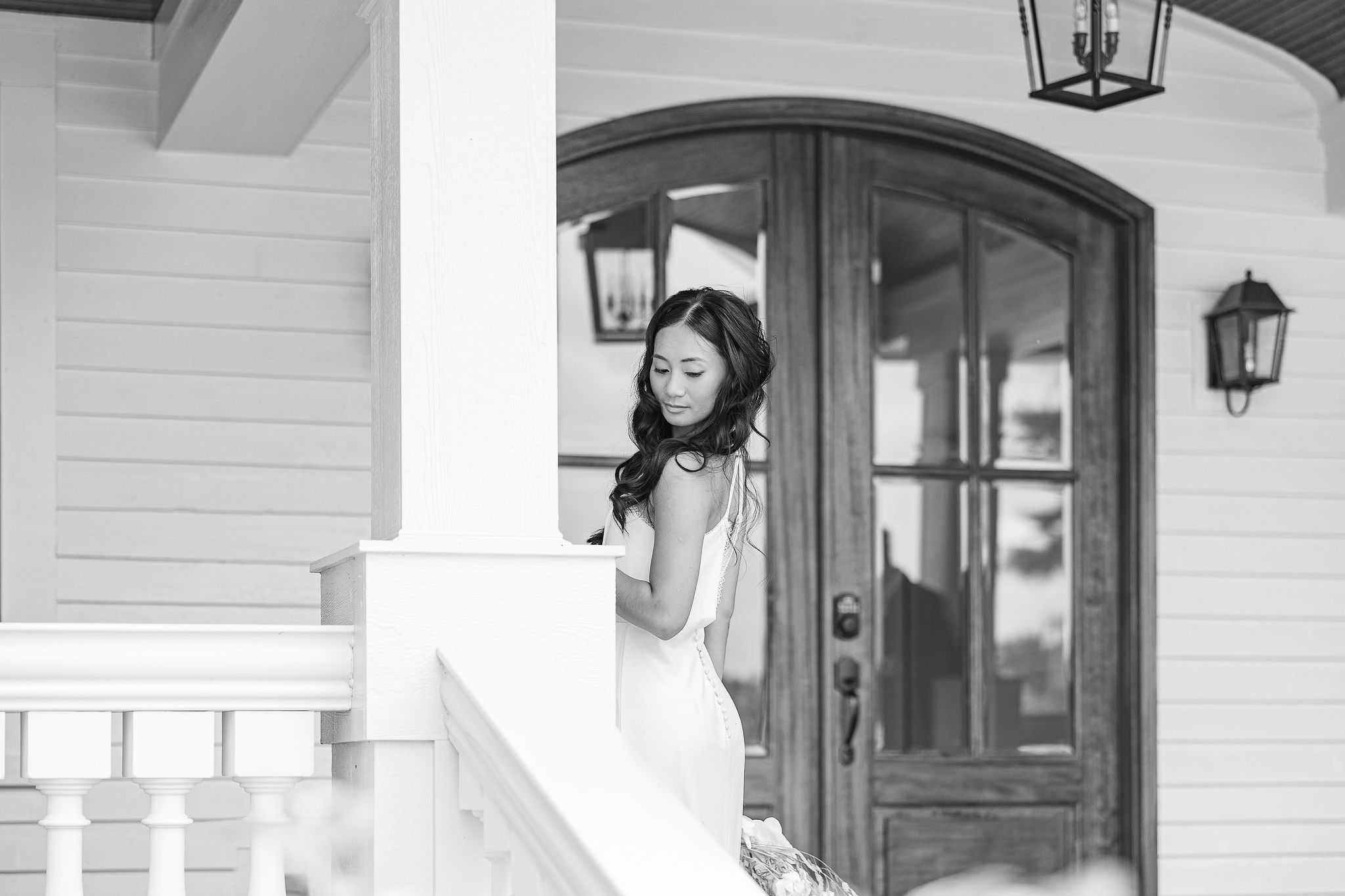 black and white photo of bride looking over her shoulder on porch