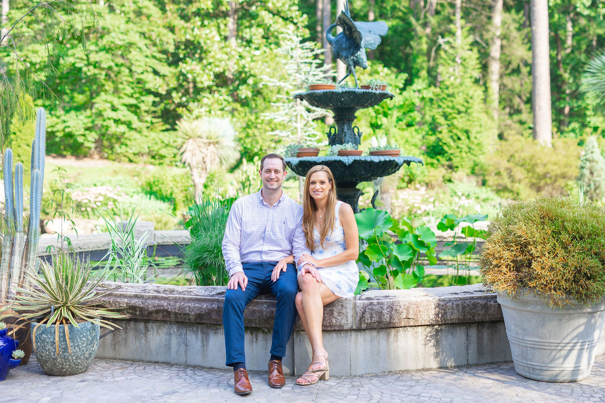 Engaged couple sitting on fountain bench at the Duke gardens in Durham, NC