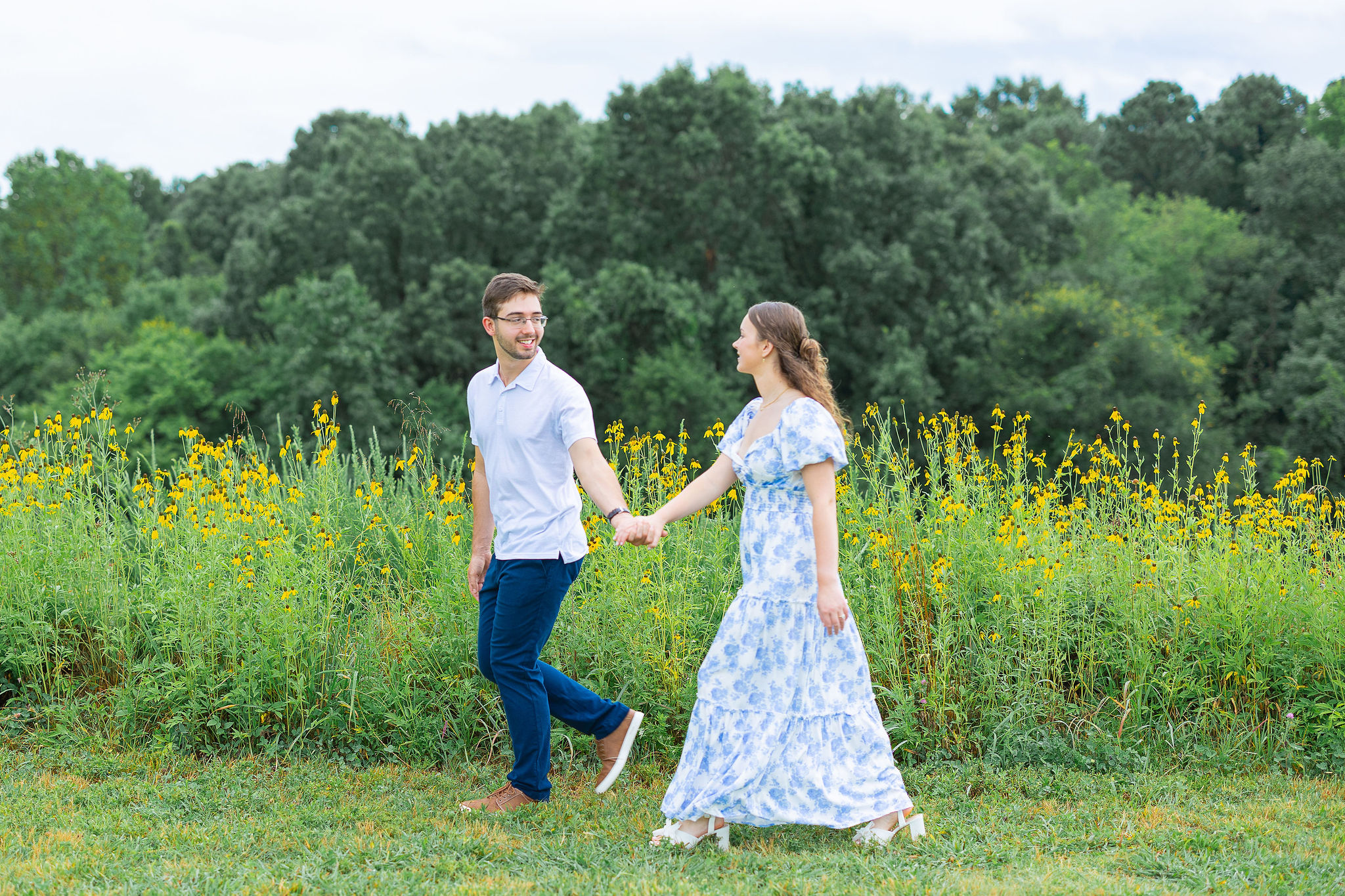 Couple in field holding hands and walking
