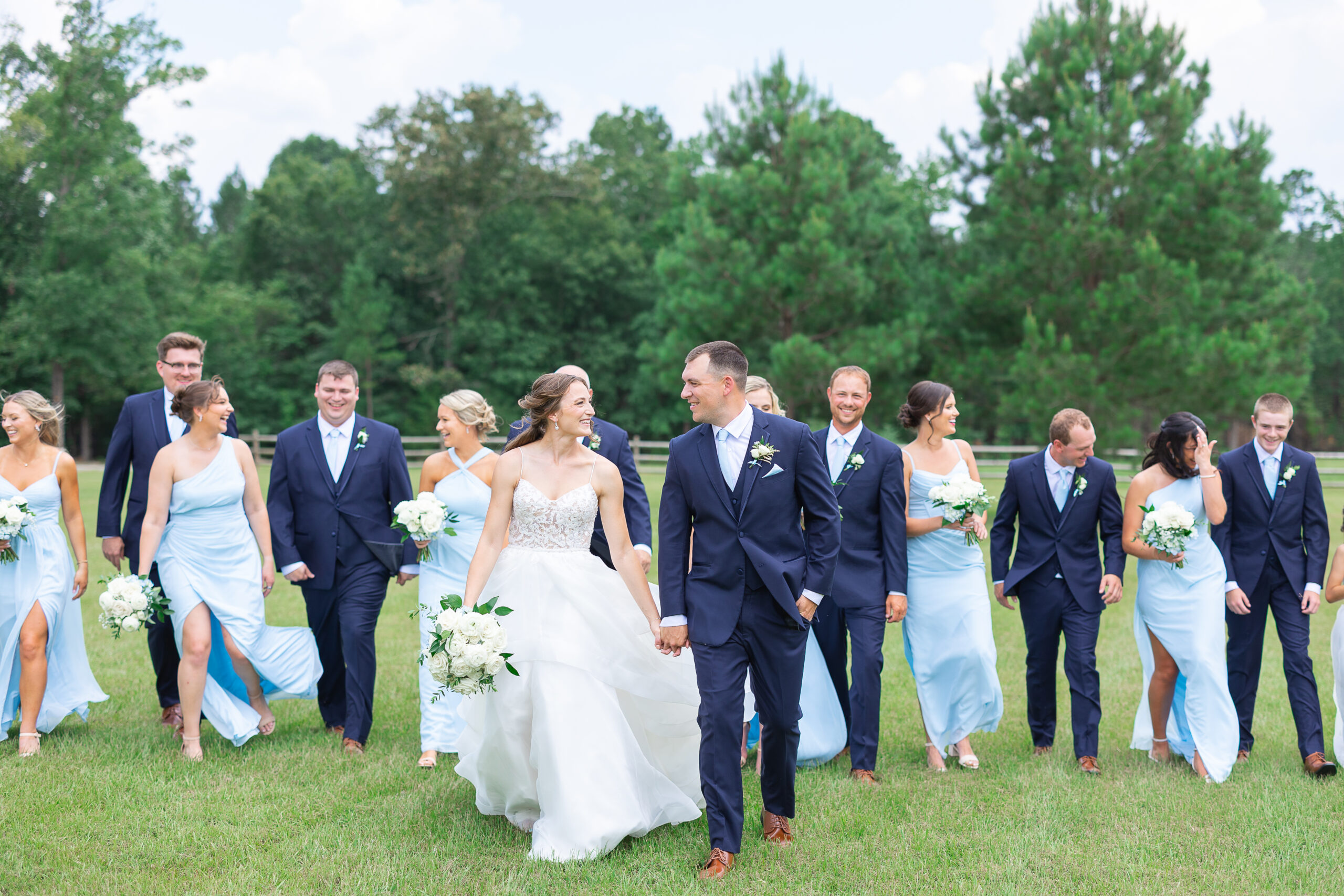 Bride and Groom walking together with bridal party behind them