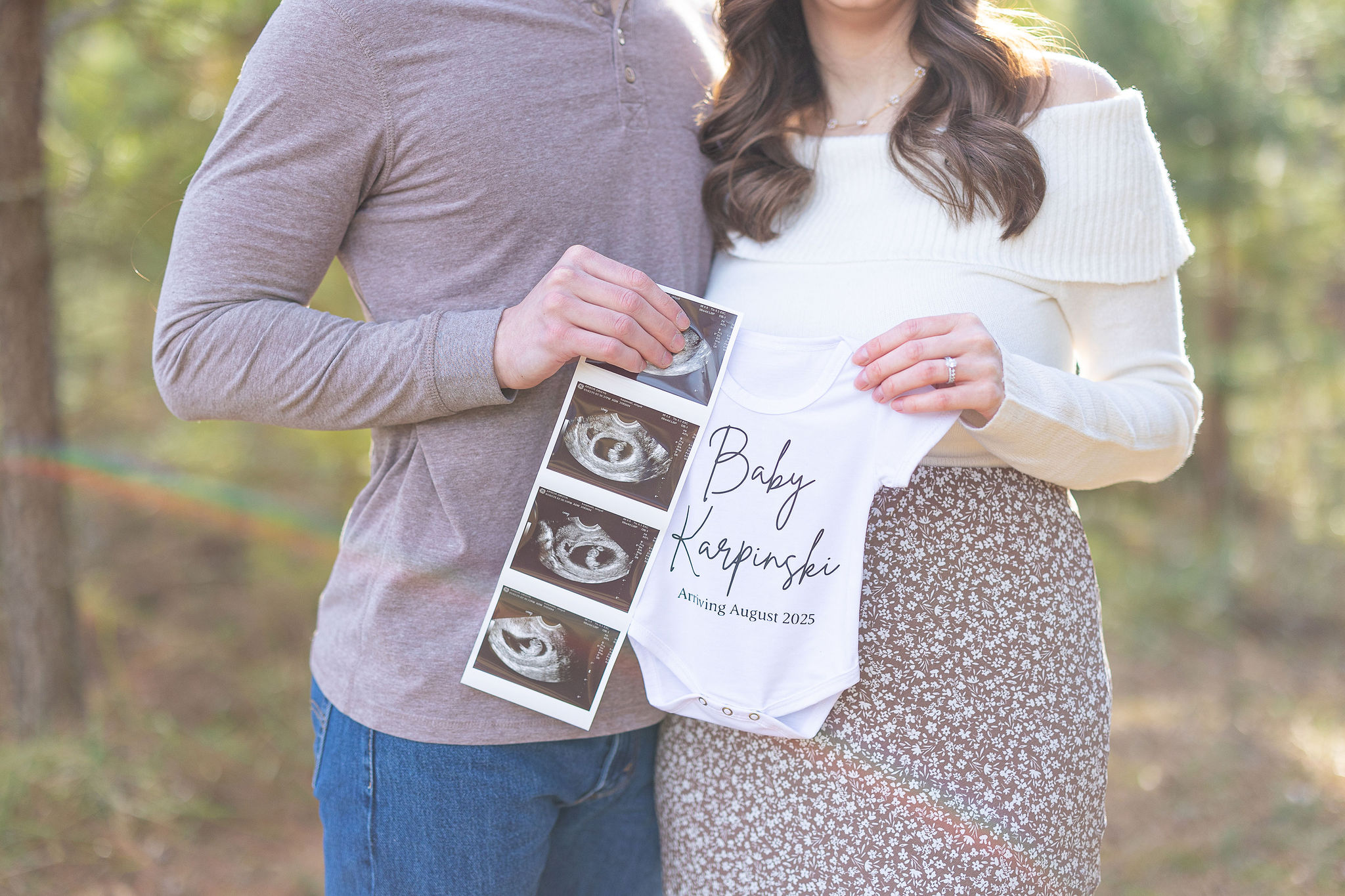 couple holding sonogram and baby onsie