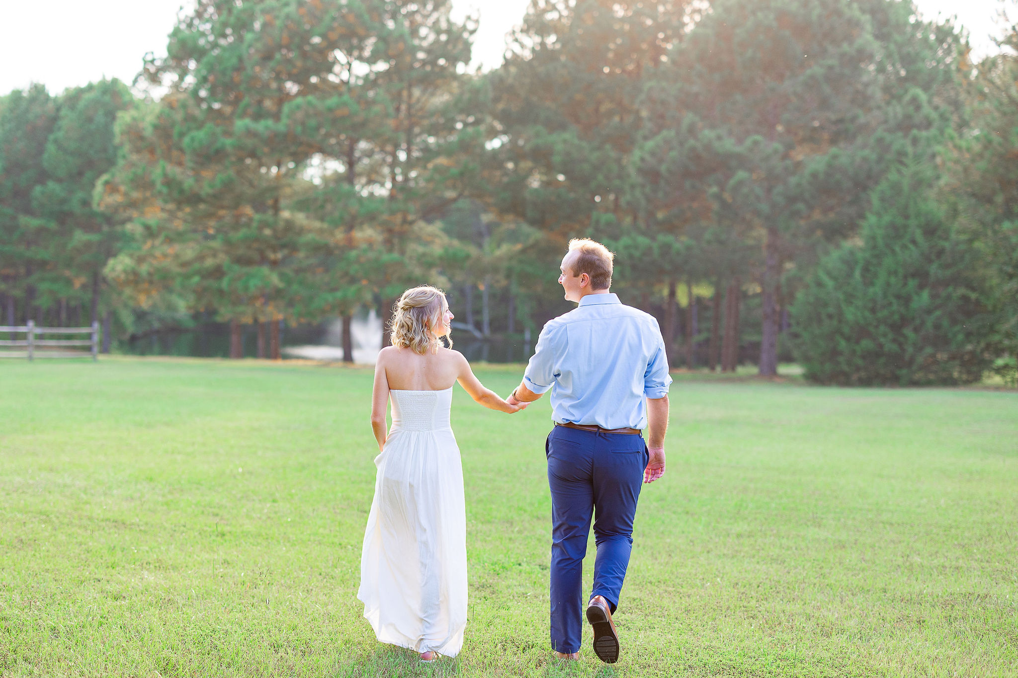 couple holding hands walking in field