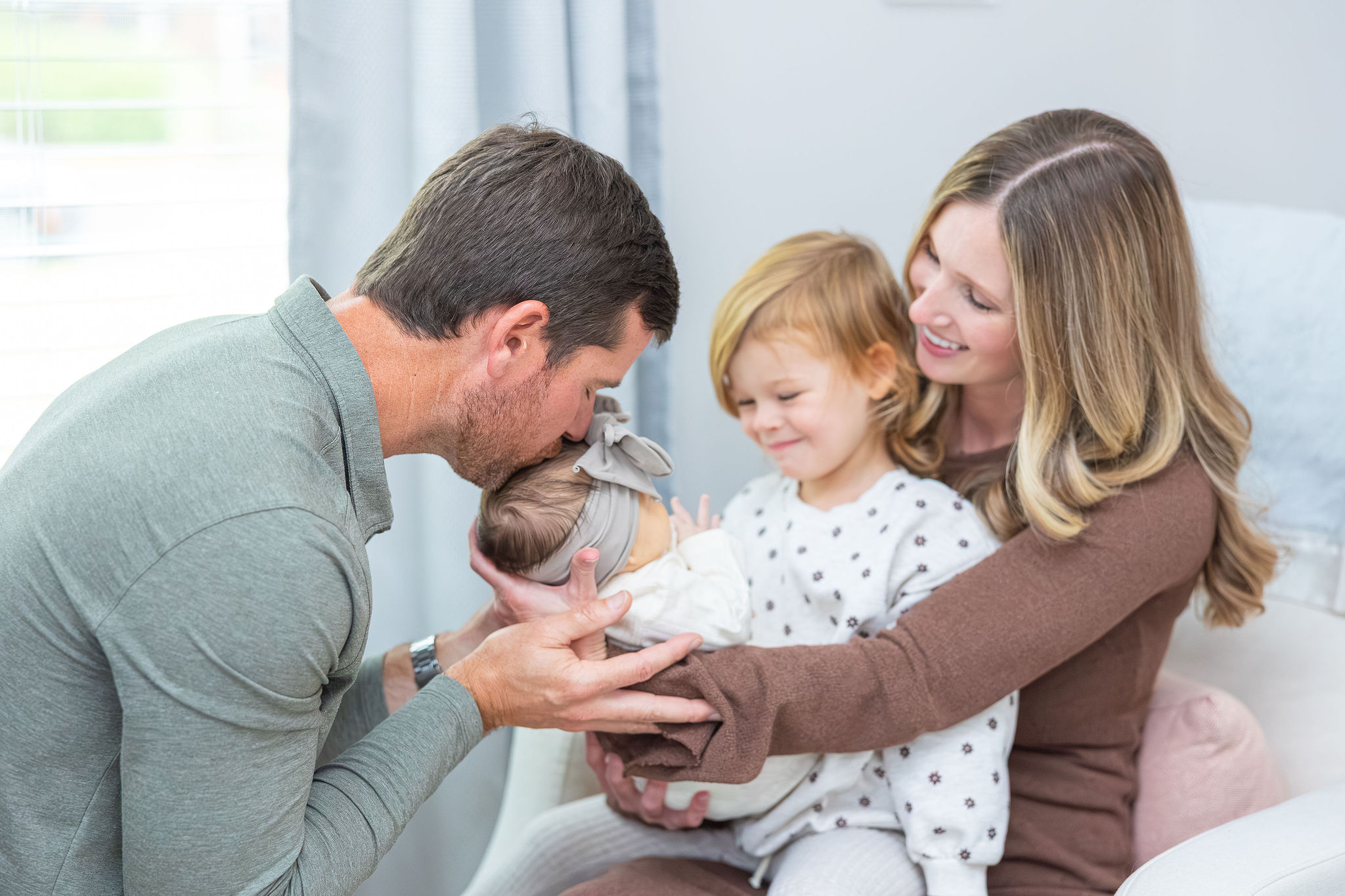 Family kissing Newborn Baby