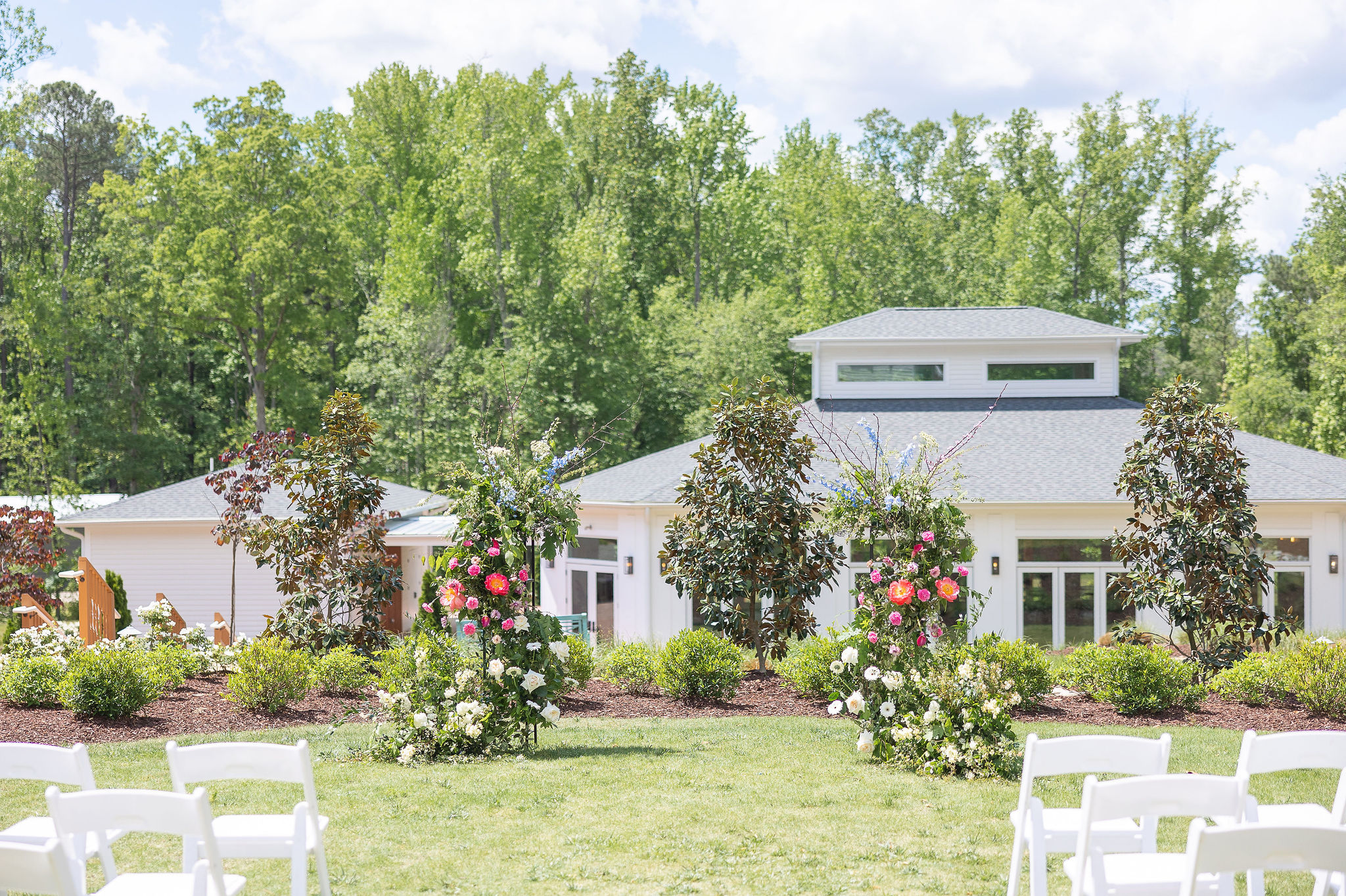 outdoor white wedding venue on lawn with flowers and chairs