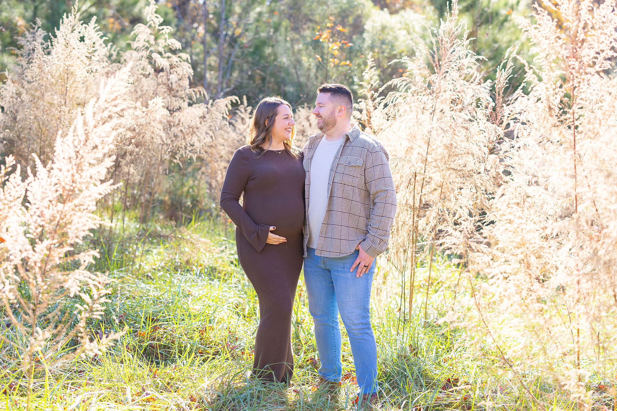 Husband and wife in field for maternity photos