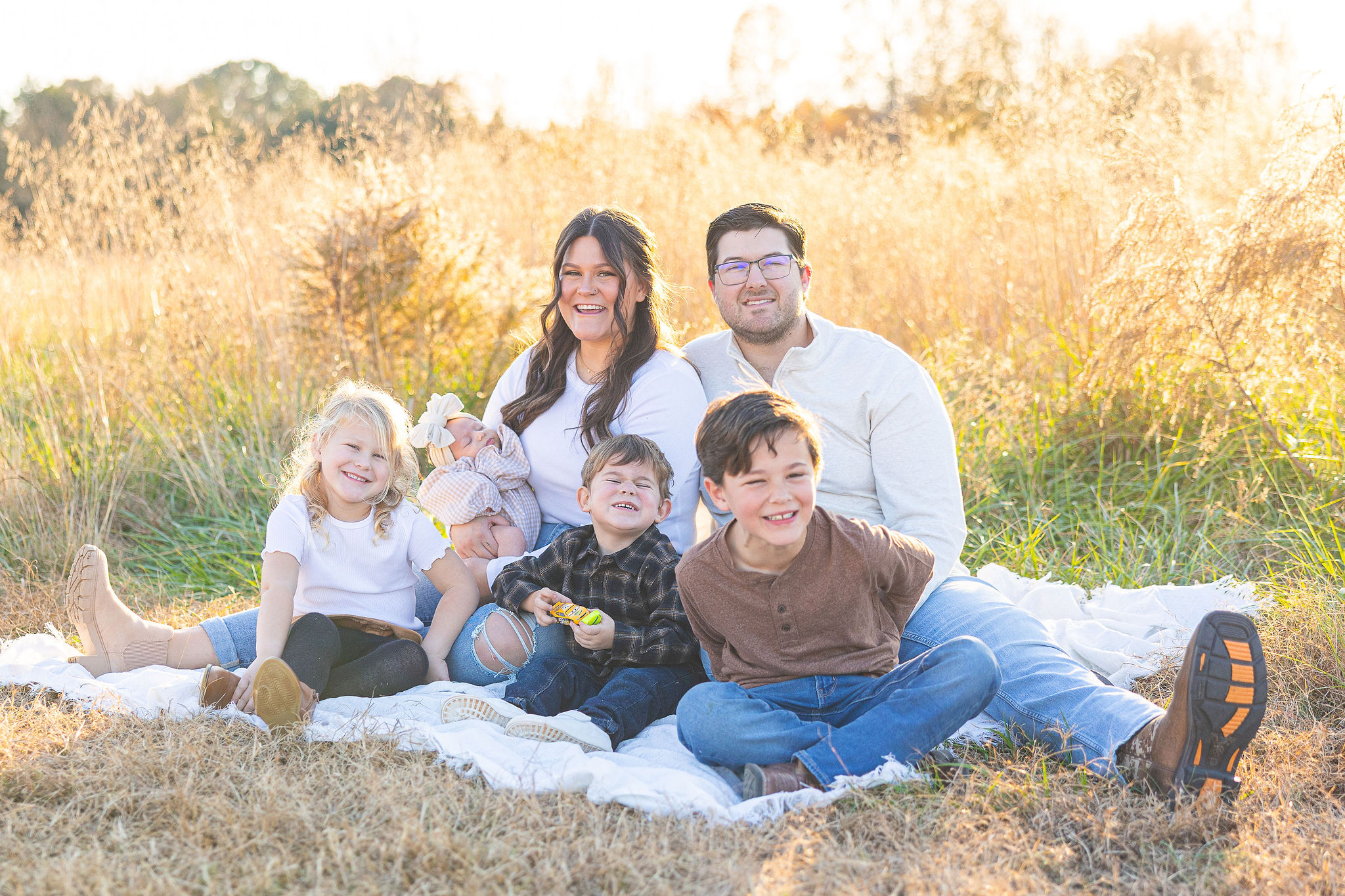 family sitting together on blanket at park
