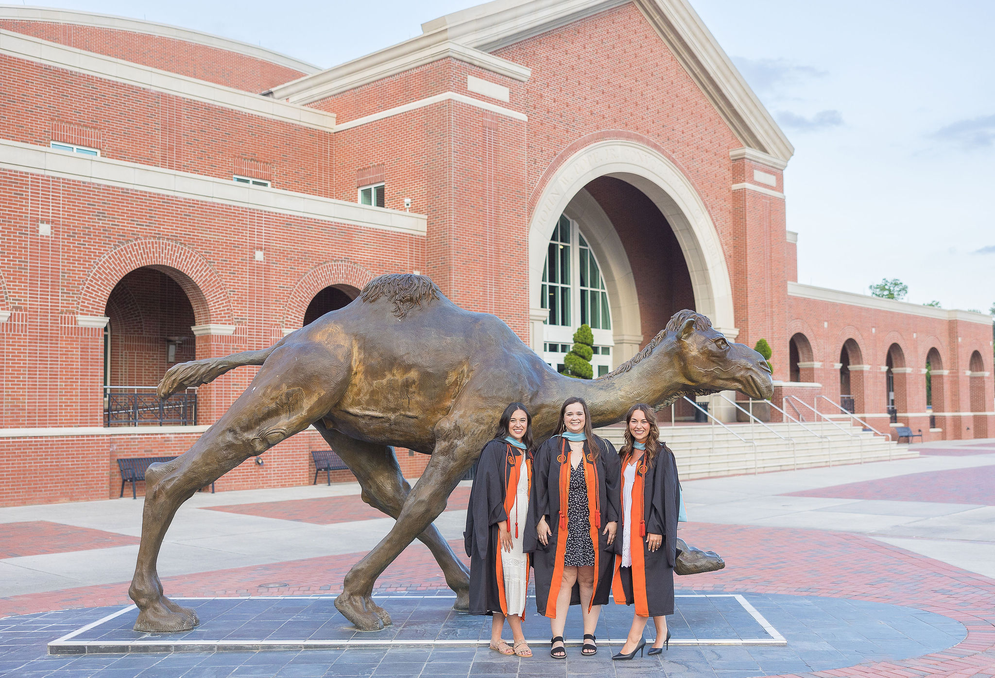 three girls standing in front of bronze camel at Campbell University for college graduation photos