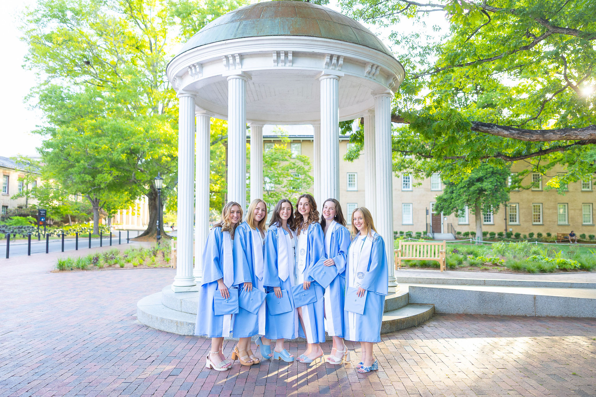 UNC grads standing in front of Old Well on Blue graduation gowns