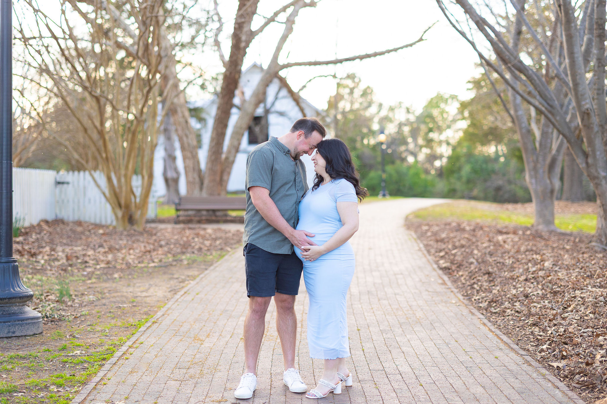 couple in park for maternity session, girl is wearing blue dress
