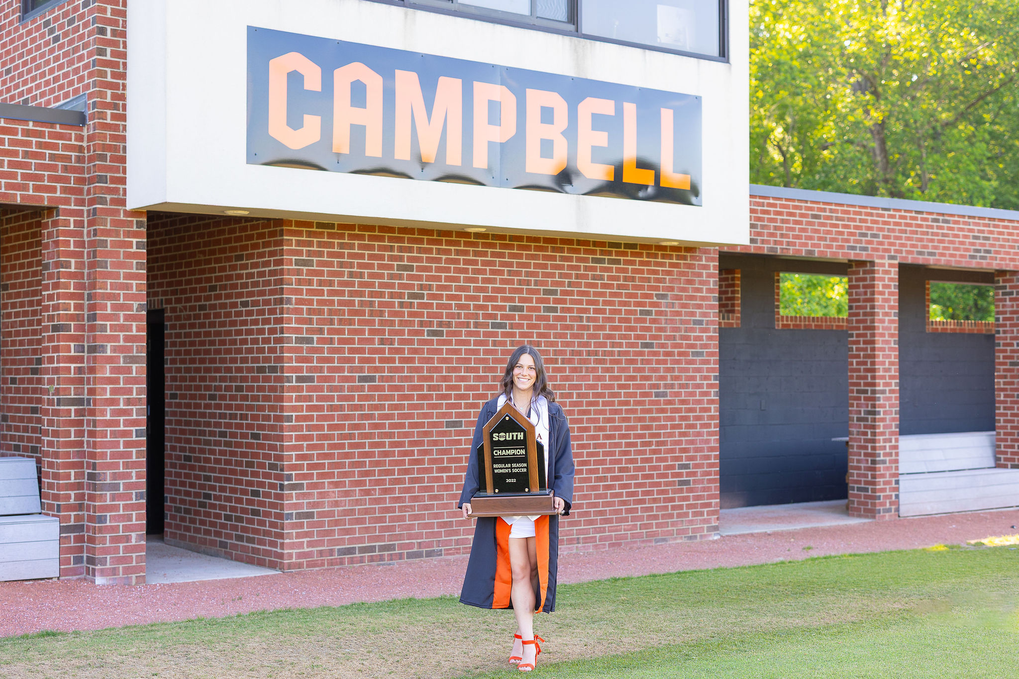 Campbell university graduate on soccer field holding trophy