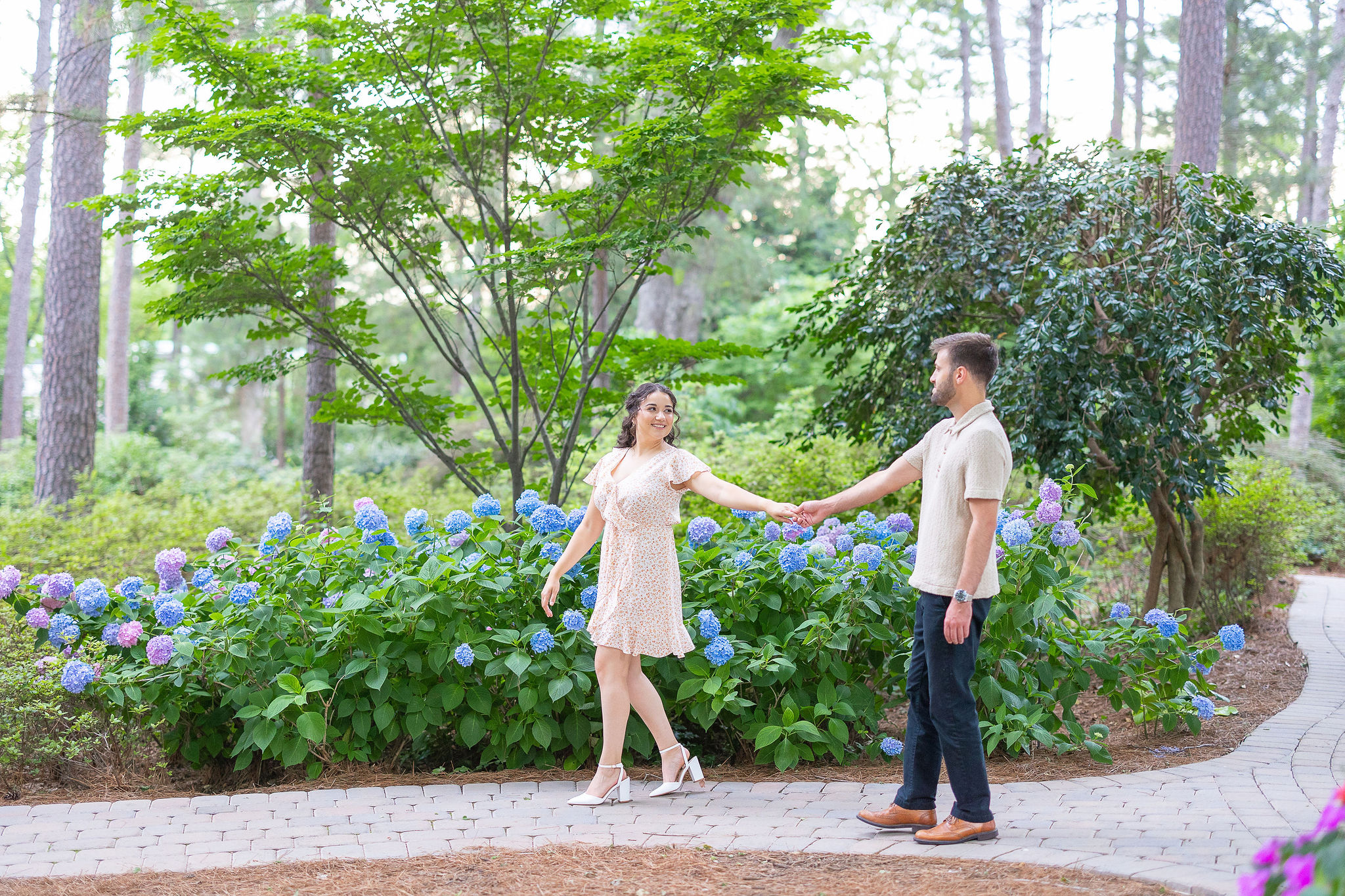 couple holding hands in front of a hydrangea bush