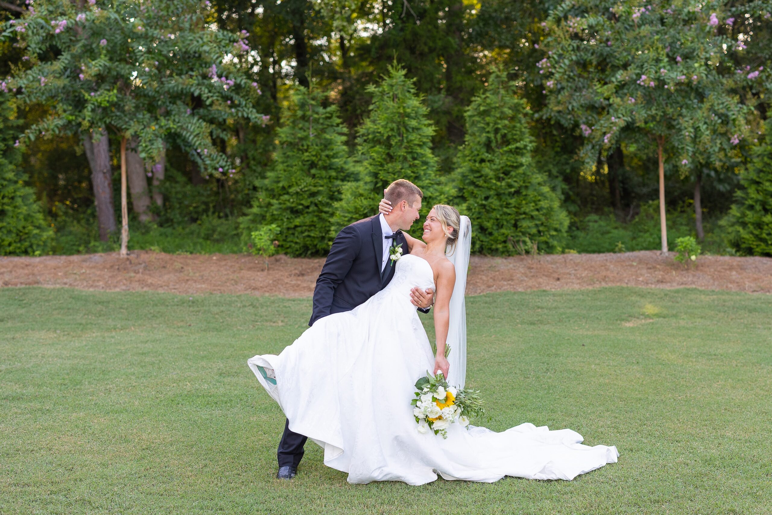 Groom dipping bride in field
