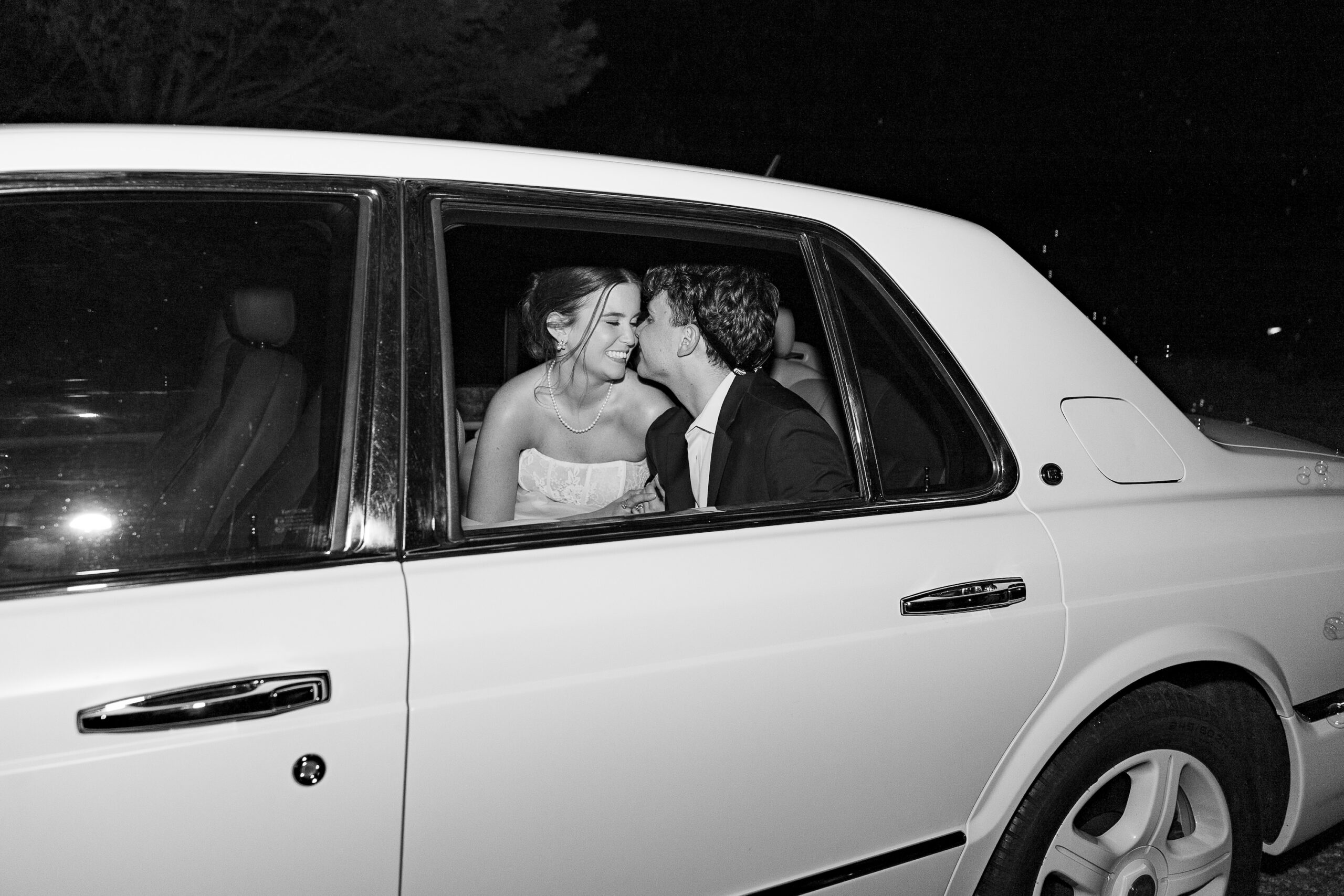 black and white photo of bride and groom in getaway car