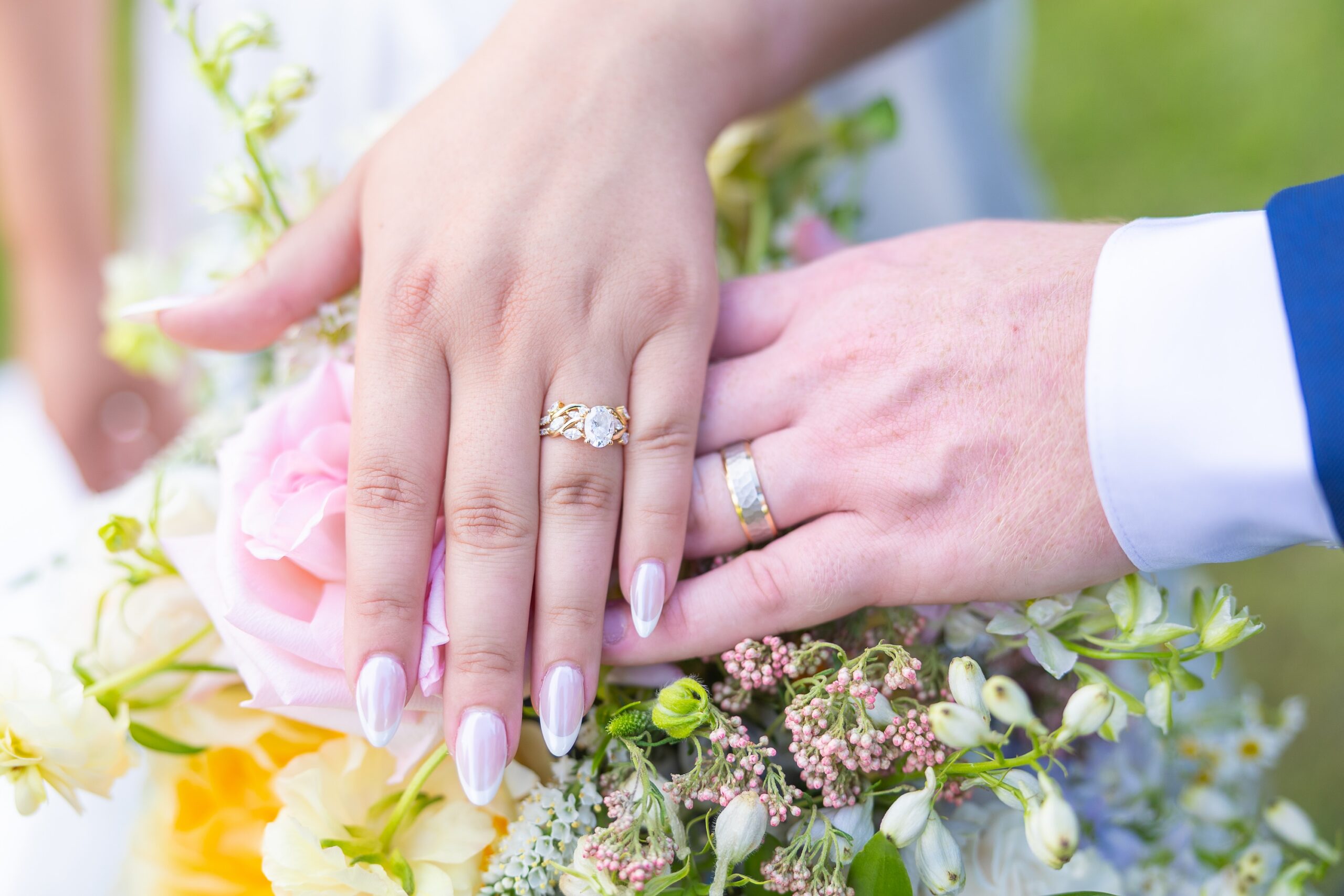 bride and groom wedding rings over flowers
