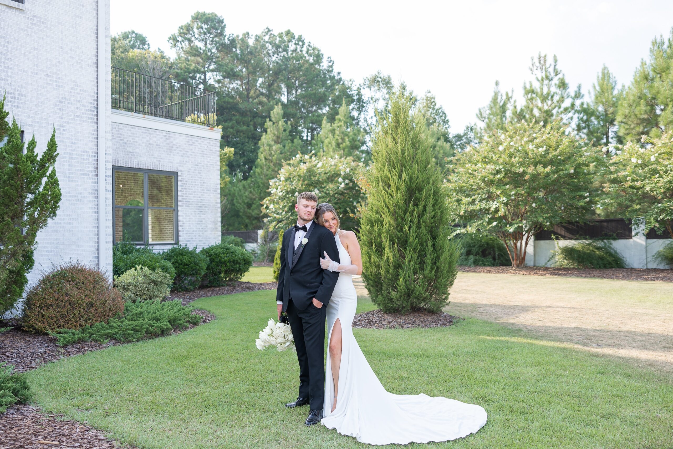 bride leaning on groom on lawn