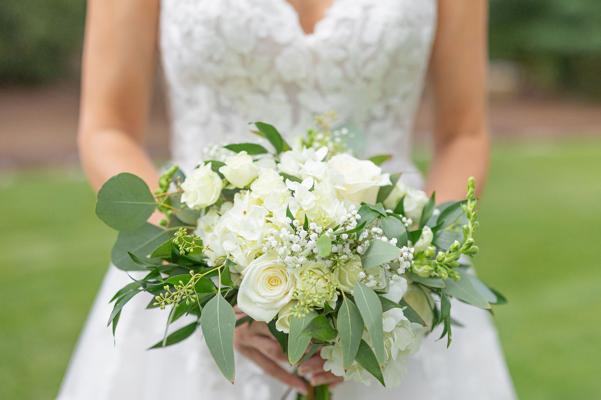 white rose bridal bouquet in front of wedding dress