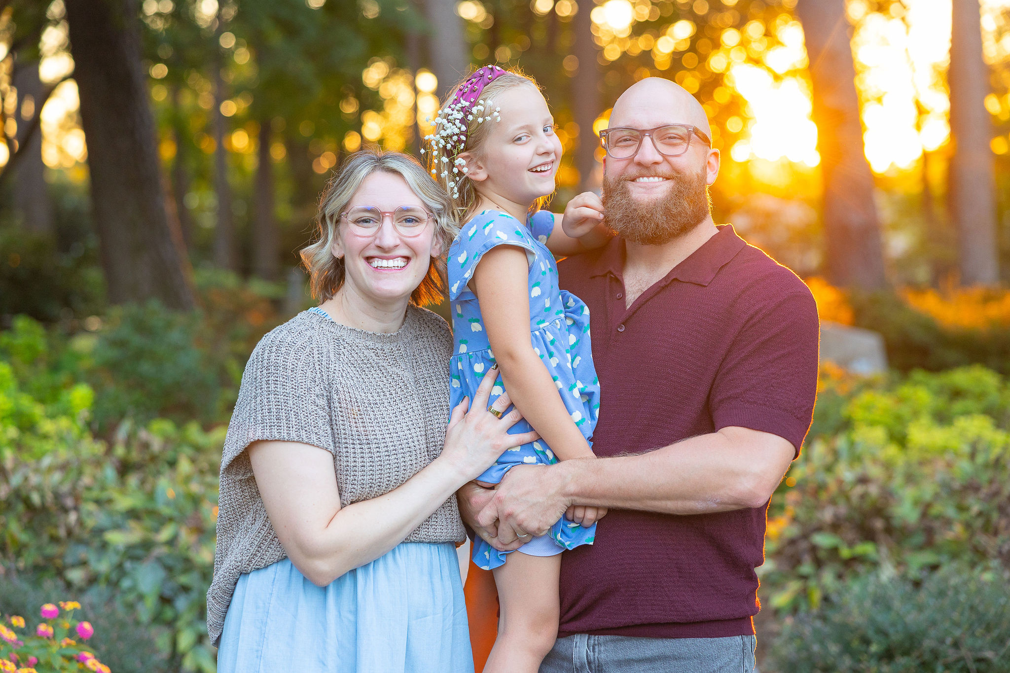 mom dad and daughter in garden at golden hour