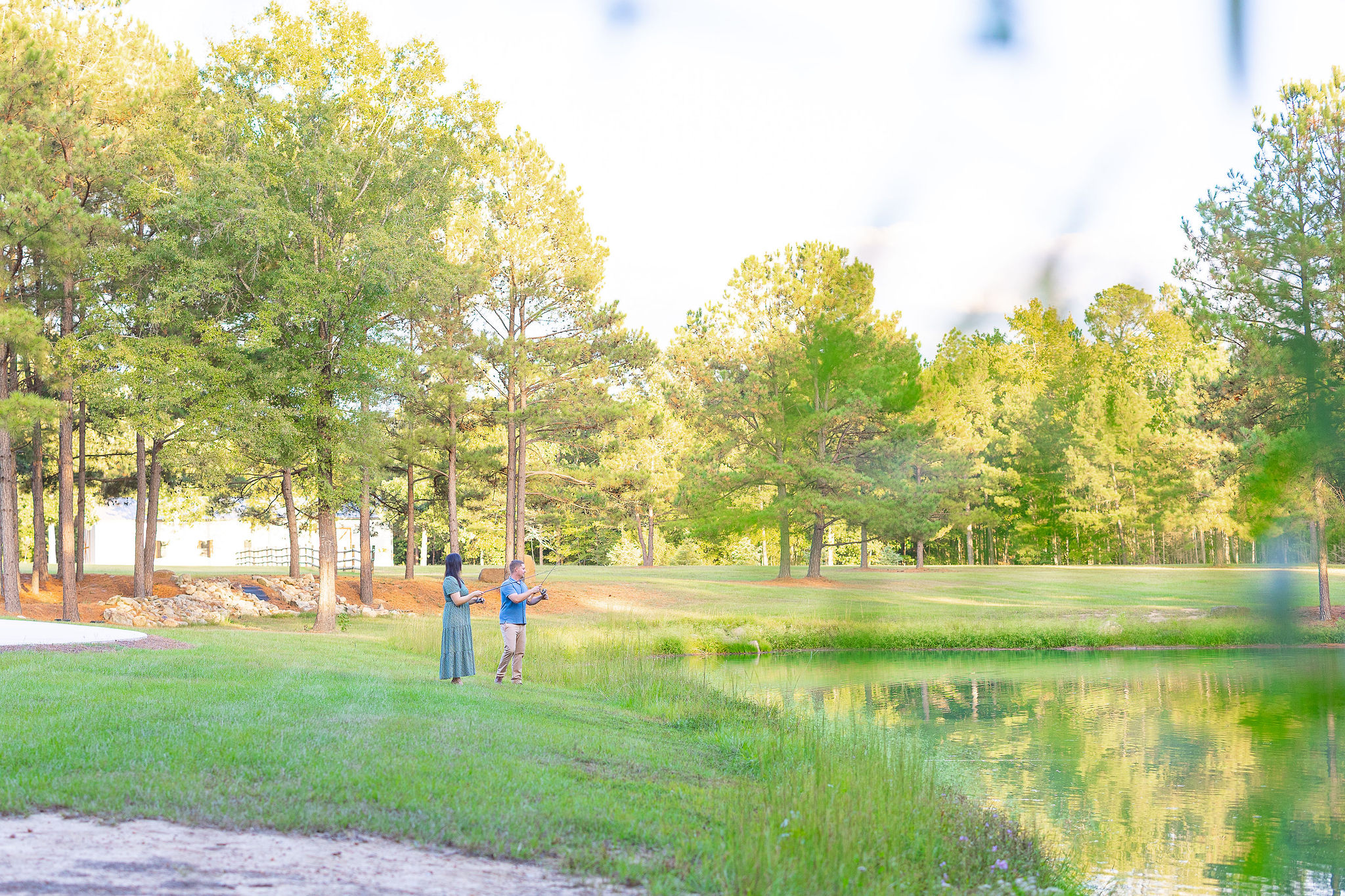 couple fishing together on lawn in front of lake