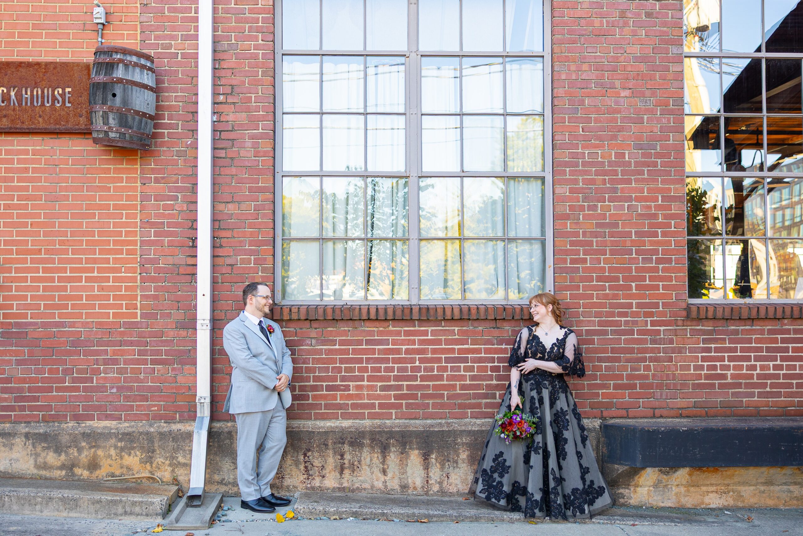 Bride and groom standing in front of brick wall