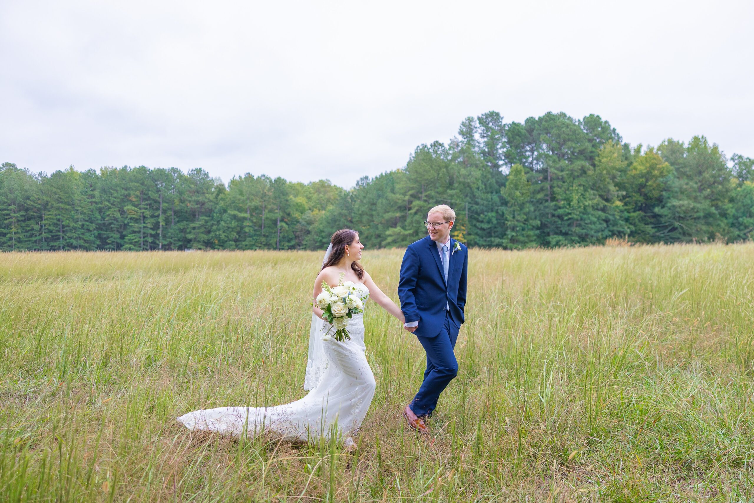 bride and groom walking in field